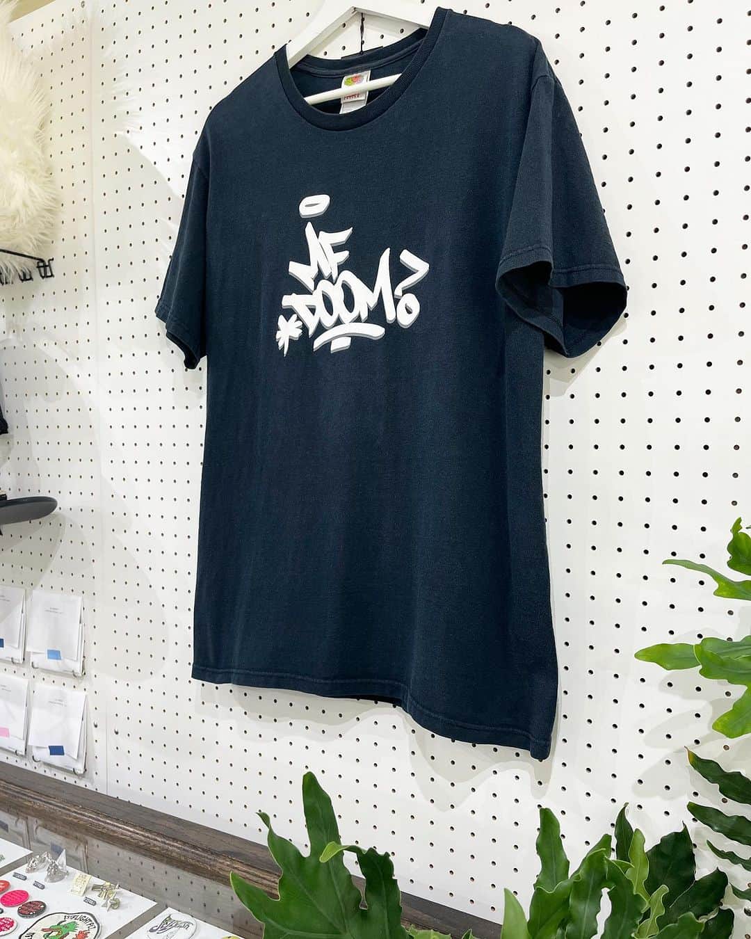 ジャムルのインスタグラム：「2000's～ MF DOOM ¥20000+tax(22000) . ロンドン生まれNew York育ちのHip Hop MC / トラックメイカー（ビートメイカー）MF DOOM。 1980年代後半からHip Hopグループ「KMD」のZev Love Xとして活動していましたが1993年に同じくKMDメンバーだった実弟が交通事故により他界しグループは活動休止に。 その後一時期はホームレスを経験するなど、どん底までおちましたが90年代後半にマスクを着用した姿のMF DOOM名義でアングラシーンにカムバック！  HIP HOPの歴史に名を残す傑作を次々とリリースし彼が生み出す独創的な世界観とビートは高い評価を受けていましたが残念ながら2020年に49歳という若さで亡くなりました。  こちらは2000年代初頭のキャリア絶頂期を迎えていた頃のMF DOOMのTシャツ。 シンプルなタギング・ロゴが無茶苦茶クールな1枚です！  近年のHip Hopアーティストの中でもN0.1と挙げる人も多いMF DOOM。  海外では日本の倍の価格でもすぐにSOLDになってしまう程人気の高いアーティスト。 それ故に今後も入荷の機会は少ないと思います、この機会に是非！！ .  WEB SHOPに入荷しております。 是非ご覧ください。 jammru.com  #お問い合わせはお電話で承ります #jammru#jammru_tee#vintagetshirt #vintagetee#mfdoom#raptee#raptees #osaka  #fashion  #streetstyle  #streetfashion  #vtg  #vintage  #used  #usedclothing  #古着 #古着屋 #ファッション #70s #80s #90s」