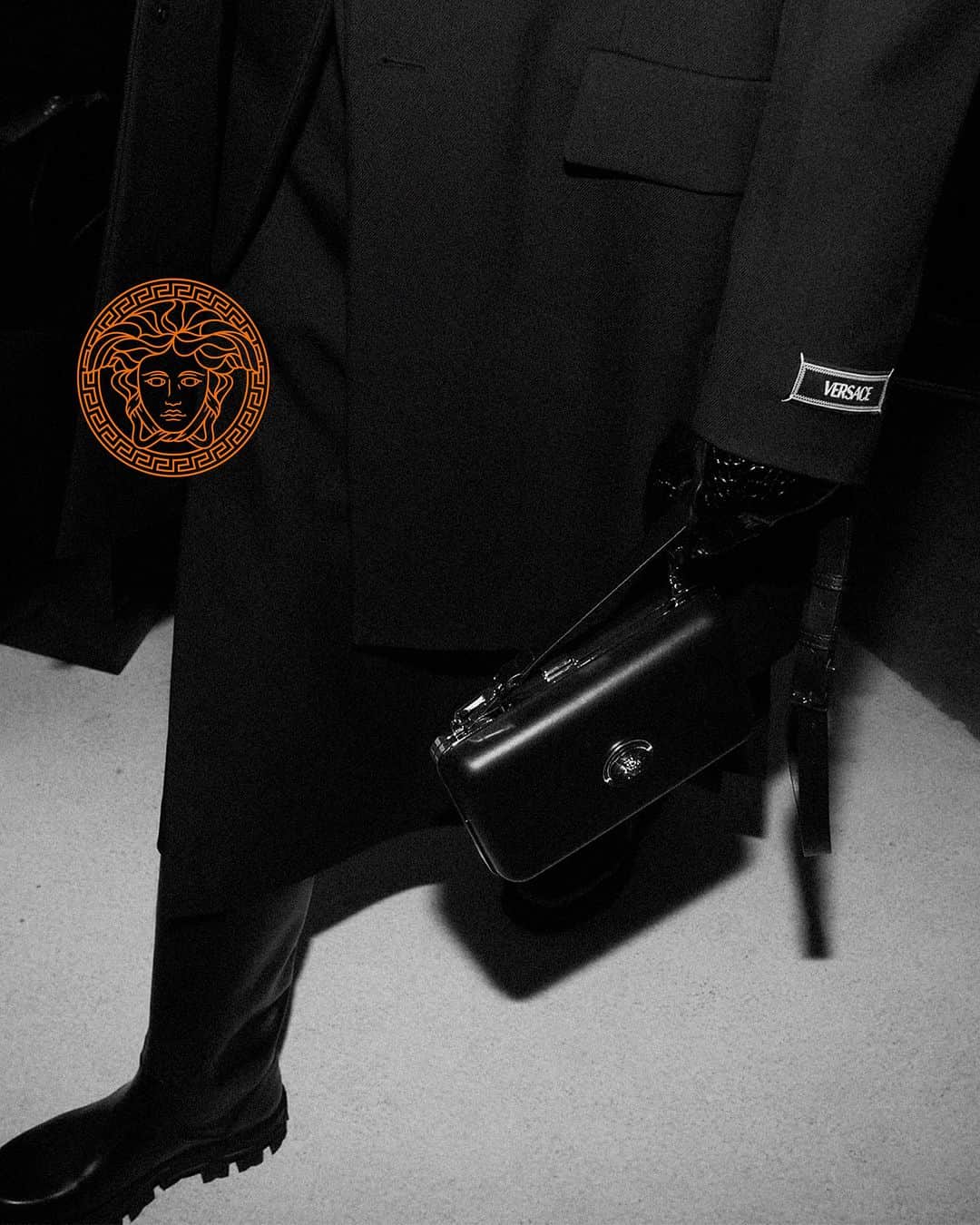 ジャンニヴェルサーチのインスタグラム：「Backstage Fall-Winter 2023  Model wears tailored coat; single-breasted tailored jacket; croc-embossed leather gloves; Greca Portico boots; Medusa Case Messenger Bag  Photography by Cameron McCool  #VersaceFW23」