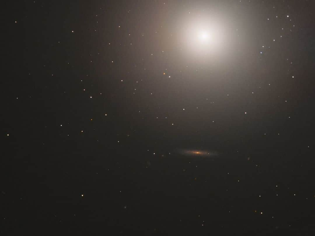 NASAさんのインスタグラム写真 - (NASAInstagram)「There’s more to it than meets the eye! 👀   In this Hubble image, there are around 100 billion stars! This elliptical galaxy known as Messier 89 was discovered by astronomer Charles Messier in 1781 and holds the record for the most perfectly spherical galaxy in his catalog of 110 objects. 🌟   Image description:  A bright, hazy ball of light shines at the top right of this image. The rest of the image shows stars against black space, with a distant, orange galaxy near the center.   #NASA #Hubble #Space #Stars #MessierCatalog #Galaxy」9月4日 1時19分 - nasagoddard