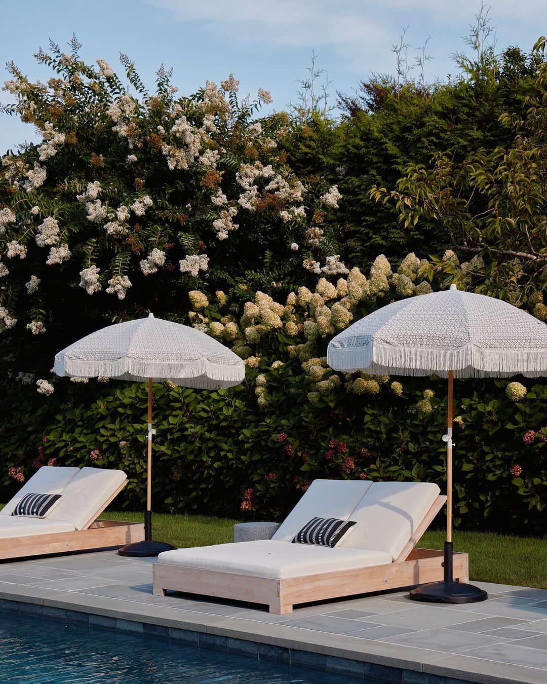 のインスタグラム：「Whether you’re lounging poolside somewhere with a cocktail in-hand, or off on an adventure this Labor Day, we hope you’re making the best of your out-of-office freedom. The homeowners of this backyard space in Amagansett, New York, certainly have an oasis to run away to. When envisioning the layout, Bespoke Only’s (@bespokeonly) Melissa Lee encouraged her clients to consider how the invisible details in the background form the experience overall. “I asked, ‘What is most comfortable for guests? And what offers a true retreat?’” The resulting resort-style lounge opportunities, connected by landscaped paths and bushes of blue hydrangea, is the perfect answer.  Click the link in our bio to tour the rest of this idyllic hedge-framed property. Written by @rachelesilva_. Photographed by @william.jess.laird.」