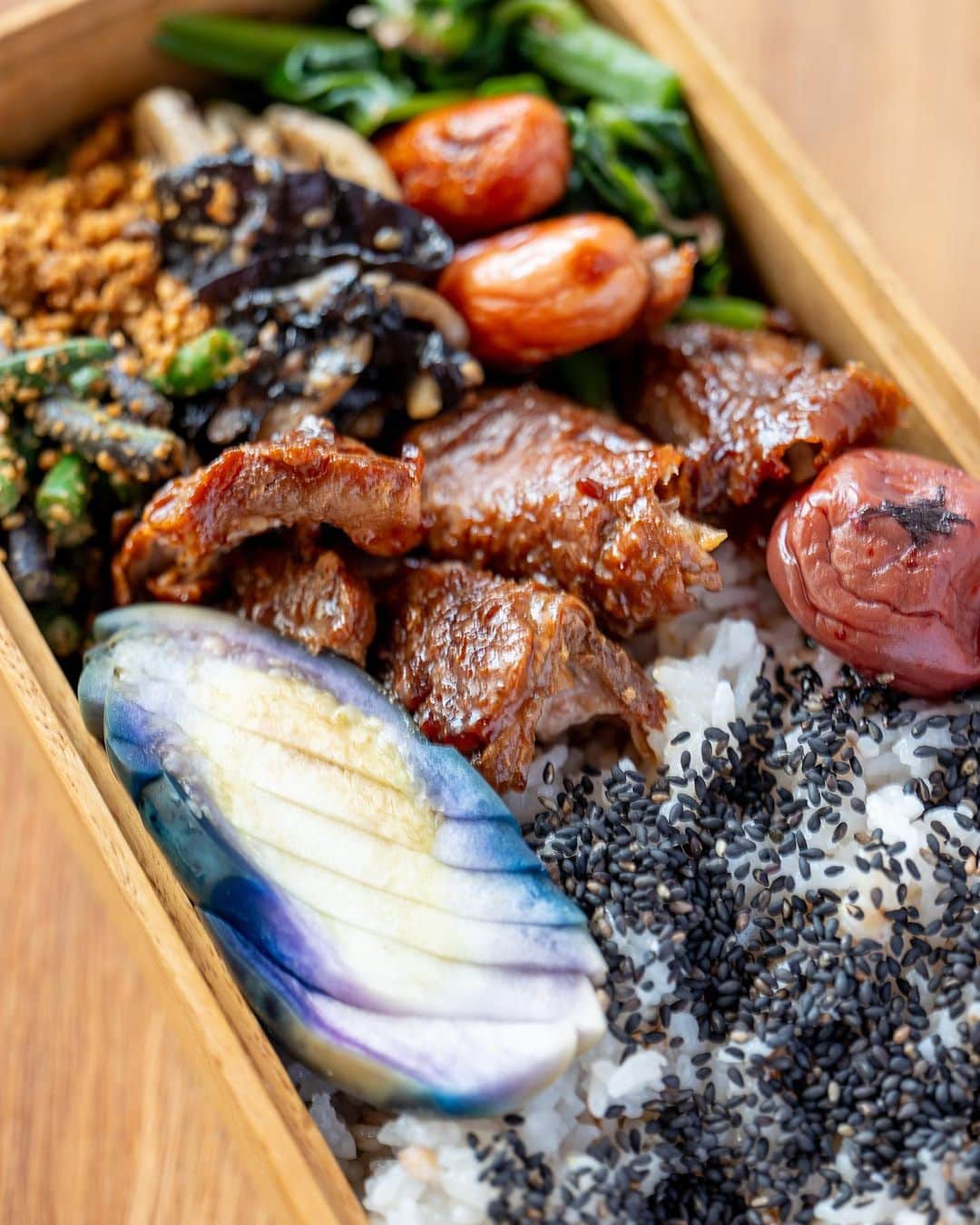 武井義明のインスタグラム：「Today’s bento.  もち米ともち麦を加えて炊いたごはん、きのうの鶏ももの照焼きのほぐしたの、焼いたソーセージ、ツルムラサキのおひたし、レンコンと乾物のきんぴら、ささげの胡麻和え、茄子の糠漬け、梅干し、黒胡麻。  Shooting at an angle or straight up?　I am often asked, "Which is better?" When I take a photo of food, if I take it from an angle, it is a "Let's eat!" while a photo taken from directly above will be an introduction of the contents, saying, "Here is what we are going to eat." I think it depends on what you want to convey.  #leica_photos #leicaphoto #leicaphotography #leicasl #leicasl601 #foodphotography #foodphotographyandstyling #bento #lunchbox」