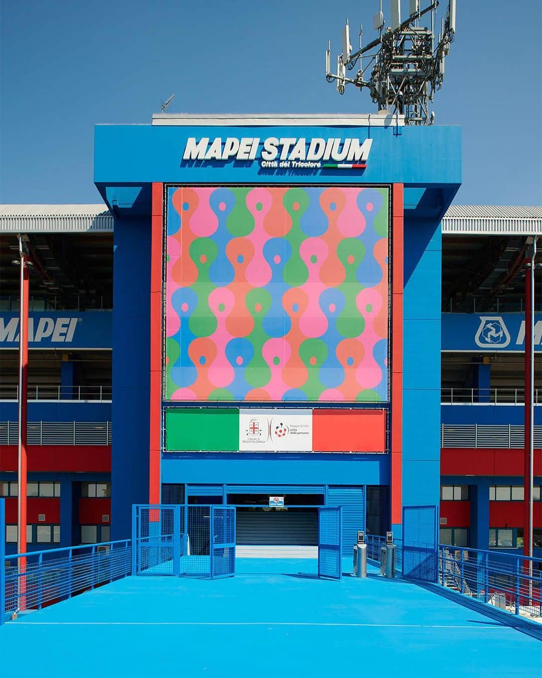 USサッスオーロ・カルチョのインスタグラム：「𝘼𝙡𝙡 𝙩𝙤𝙜𝙚𝙩𝙝𝙚𝙧 𝙣𝙤𝙬 🫂  La facciata principale del #MapeiStadium ospita, insieme al tricolore, l’illustrazione "All together now" di @olimpiazagnoli, artista di fama internazionale.   L'ispirazione nasce da un video in bianco e nero del 1964 nel quale i tifosi del Liverpool cantano all’unisono "She loves you" dei Beatles dalle tribune di Anfield.  “È una ripresa che riguardo di tanto in tanto – racconta Olimpia Zagnoli – e che mi colpisce perché da essa traspare un certo romanticismo che credo sia necessario per affrontare tanto le vittorie quanto le sconfitte allo stadio e nella vita. L’illustrazione rappresenta un gruppo di persone eterogeneo catturato nell’atto di celebrare un sentimento comune in un preciso momento e in un preciso luogo. Un coro di voci diverse che si alza in cielo e si unisce”.  #ForzaSasol 🖤💚 @mapei_italia Credit 📸 Filippo Vinardi」