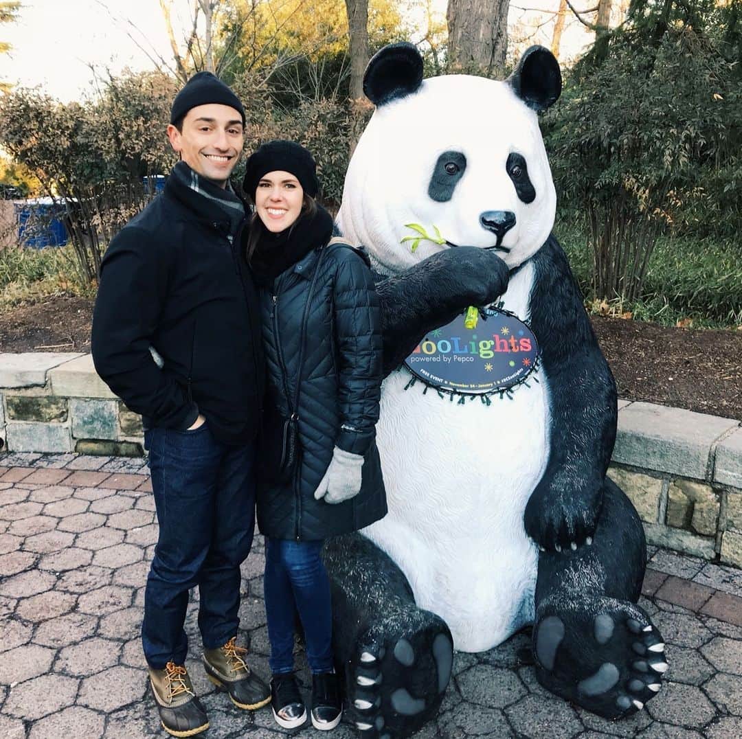 スミソニアン国立動物園のインスタグラム：「In honor of our giant panda program, we asked for your favorite memories of the Zoo's giant pandas over the decades. These are your stories. 🐼 #PandaPalooza  "When I was in my mid-20s and living in Mount Pleasant, I loved taking long runs to and then through the National Zoo. My goal was to run from home, through Rock Creek Park, all the way to the panda exhibit. Seeing the pandas was my long-run reward.  When I was 26 and visiting Seattle, I met a very smart and charming man at a Christmas party. We hit it off, and while chatting, I shared how much I loved running to and through the National Zoo to see the pandas. He had never seen pandas in real life and joked that he had to come visit me in DC (to see the pandas, of course). We exchanged numbers, but since we lived in two different Washingtons, I didn’t think much would come of it.  I was pretty smitten though, and apparently, so was he. Just a couple of weeks later, the very smart and charming man booked a trip to DC to “visit a friend.” Since he was in town though, he wanted to know if I still wanted to show him the pandas. And of course, I said yes.  We walked to and through the zoo and watched Bei Bei the panda rolling around in the grass. We laughed a lot, and he held my hand. The attached picture is our first picture together as a couple. Several years later, we still have the pandas from the National Zoo to thank for bringing us together." Submitted by Laila H. of California.  Come see our pandas before they depart, by reserving your free entry pass using the link in our bio! 🔗   Image description: a photo of a man and woman smiling and posing next to a giant panda statue.」