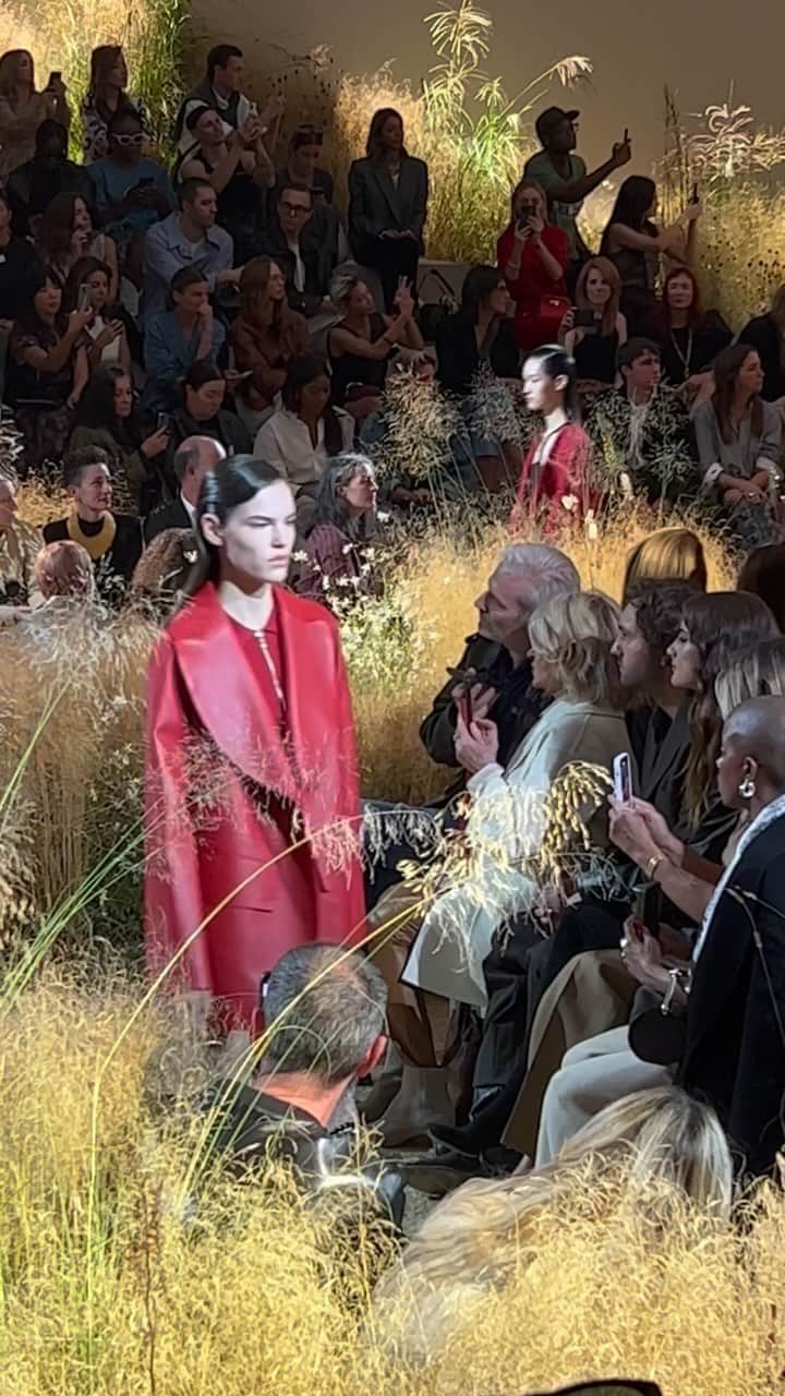 のインスタグラム：「小鳥のさえずりが響く草原が、エルメスの2024年春夏コレクションの舞台。「即興のピクニック」を着想源に掲げたアーティスティック ディレクターのナデージュが描いたのは、ワインレッドやストロベリーレッドに染まる赤、そしてトープなどのグレー～ベージュを軸とした、情熱的かつシックなワードローブ。腰回りやデコルテの素肌を見せたセンシュアルなカットも特徴的。足もとはノンシャランなサンダルが多く、干し草をバケツ型のバッグとともに、穏やかな午後のピクニックスタイルへといざなって。#SS24 #HERMES #PFW」