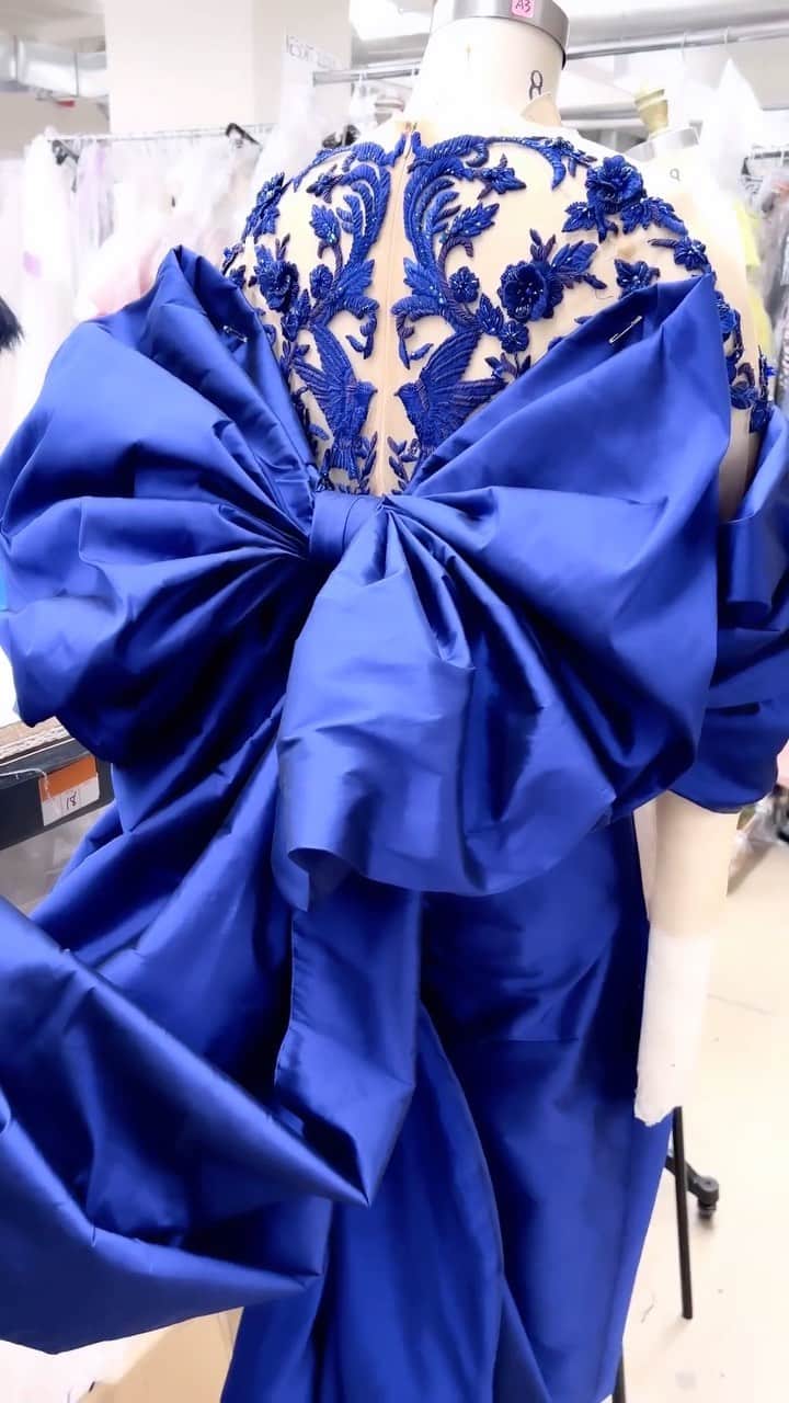 のインスタグラム：「A look inside the #MarchesaAtelier, the design team crafts the Fall 2023 Marchesa collection. The taffeta bow gown features a luxurious cold shoulder chenille base, adorned with intricate beadwork, bullion detailing, and exquisite threadwork that brings to life a breathtaking 3D rose and bird embroidery. The gown flows gracefully with a sumptuous taffeta skirt, and a delightful detachable sleeve integrated bow at the back.   #Marchesa #FW23Marchesa」