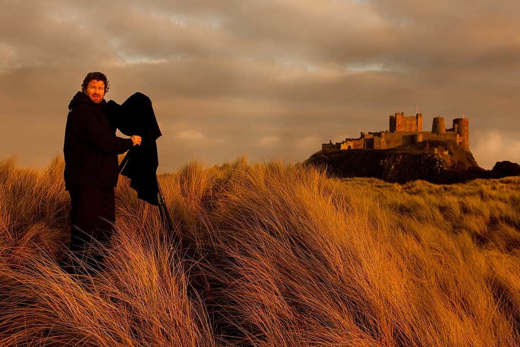 Robert Clarkさんのインスタグラム写真 - (Robert ClarkInstagram)「Here stands #BamburghCastle,  the site of at least a dozen battles for the control of the Castle and of the area in #NorthUmberland. I have delved into my archive after hunting for picture from #SycamoreGap, before the recent assault that feld one of the most beloved trees and locations in all of England. I have been looking at pictures from three different stories for #NatGeothat I have worked on in the area, an Anglo Saxons Gold Hoard, Roman Walls and the Vikings The site was originally the location of a Celtic Brittonic fort known as Din Guarie and may have been the capital of the kingdom of Bernicia from its foundation c. 420 to 547. In that last year, it was captured by King Ida of Bernicia. After passing between the Britons and the Anglo-Saxons three times, the fort came under Anglo-Saxon control in 590. The fort was destroyed by Vikings in 993, and the Normans later built a new castle on the site, which forms the core of the present one.  In more recent history, in 1894, the castle was bought by the Victorian industrialist William Armstrong, who completed the restoration, at that time the Sycamore at the Gap would have been only around 120 years old. One or the trips to the area, I was shooting my SINAR P2 & 5x4 film. The thought of the tree being destroyed still cause me pain. The photo is by @christopherfarber by colleague on this trip.:)」10月4日 3時26分 - robertclarkphoto
