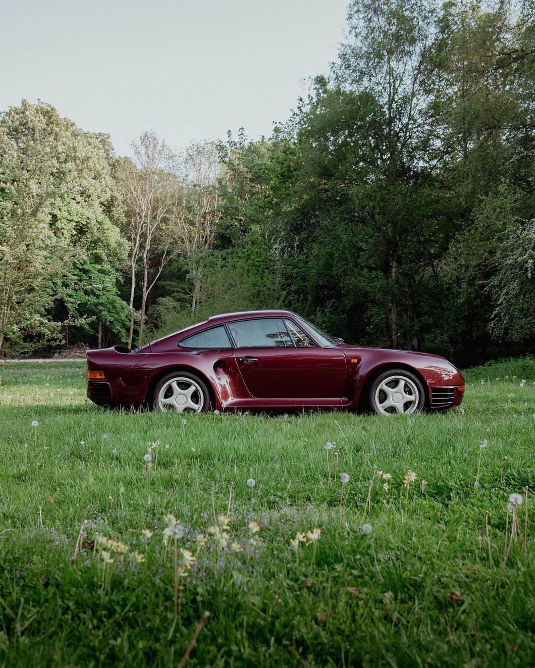 Porscheのインスタグラム：「A Porsche kind of summer.  ___ 34 years and counting. That's how long this Ruby Red Metallic 959 has been in private hands, most recently with British owner Andy. But it's not just any 959; it's a rare F7 model, a Porsche prototype built for testing and development. Spotting one is a real treat. Luckily, we caught this rare specimen prancing around a flowering meadow — just one of about a dozen that survive to this day.  📸 @machina.studios #PorscheMoment」