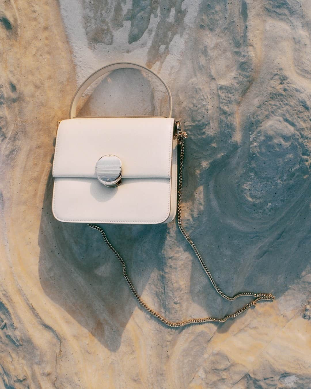 Chloéさんのインスタグラム写真 - (ChloéInstagram)「The Penelope top handle bag in ‘misty ivory’ coloured leather is depicted against the swirling patterns of volcanic rock on Milos Island in Greece.  #ChloeAW23  Creative director: @gabrielahearst  Art director: #PeterMiles Photographer: @zoeghertner  Stylist: #CamillaNickerson  Models: @raquel_zimmermann @devynfaithgarcia」9月11日 0時00分 - chloe