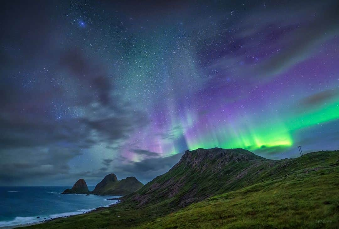 KAGAYAのインスタグラム：「海風に流れる雲。雨がやむと、雲の上に星空とゆらめくオーロラが現れました。 日本から30時間ほどかけてやってきた北の果ての光景。 強風の中、三脚をおさえながらの撮影でした。 （本日未明、ノルウェーにて撮影）  海風の夜のオーロラ　撮影データ カメラ：SONY α7R V レンズ：SIGMA 14mm F1.4 DG DN | Art 露出13秒　F1.6　ISO3200　三脚にて固定 2023年9月10日21時53分(UT)  #ノルウェー #北欧 #星空 #starphotography #sonyalpha #α7rv」