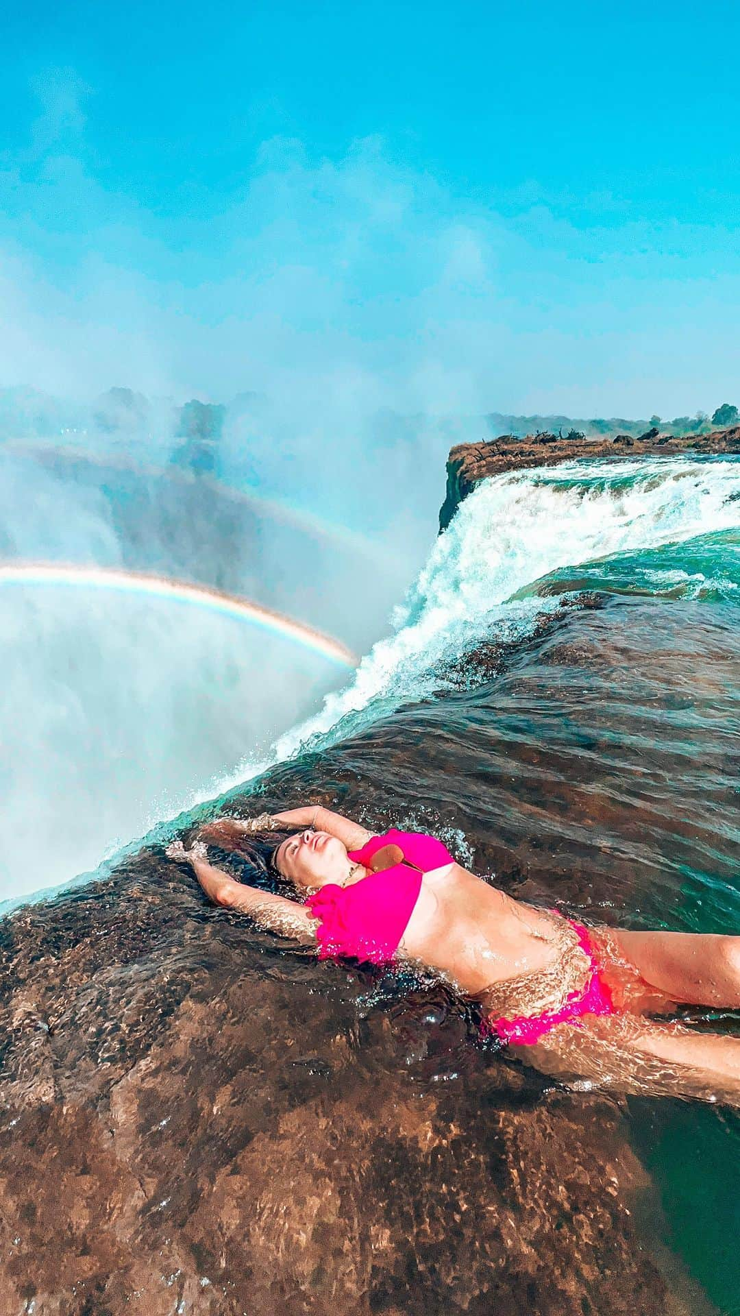 アリサ・ラモスのインスタグラム：「The Devil works hard, but these guides at The Devil’s Pool at the edge of Victoria Falls in Zambia work harder!!!!  In case you’re wondering how people get those seemingly perfect and relaxed photos there, it’s all these guys!!   First of all, you can only do Devil’s Pool during the low-water season (I’ve been during high season and had to do Angel’s Pool to avoid going over the edge), and it requires you to swim across the top of the falls in freezing water.  One guide leads the group all together, then you have to go one by one across the current to get to the rock island you can see people sitting at.  Then they have you go one by one to the edge, where one guy holds your ankles and another works his photo magic while STANDING AT THE EDGE of the waterfall!  They both will tell you to go all the way farther to the edge until you can look down and see the bottom 😱🤪🫣 which i of course did thinking it was cool, and didn’t realize others in my group were very scared of that part, so FYI you can tell them you don’t want to go as far as I did 😂  I’ve honestly never been so impressed by such strategy in such a dangerous location! And also, no, we didn’t have any ropes attached to us, we were literally just there at the edge with these guys sometimes holding on to us! (They didn’t hold me when I was just sitting up 😱)  Also yes I did a swimsuit change, since I got to go twice due to my group being split in half. I wish I got the guides IG’s but I was too cold to function, so if they see this, THANK YOU Omega!!  Would you dare swim in the Devil’s Pool???  (More BTS: I was actually very sick when I did this, and the double swim made it worse, but this was a top bucketlist check for me so I did it anyway….and was in bed by 4pm for about 16 hours afterwards!)  #devilspool #thedevilspool #thedevilspoolatvictoriafalls #victoriafalls #zambia #mylifesatravelmovie #mylifesatraveltribe #livingstoneisland #mosioatunya」