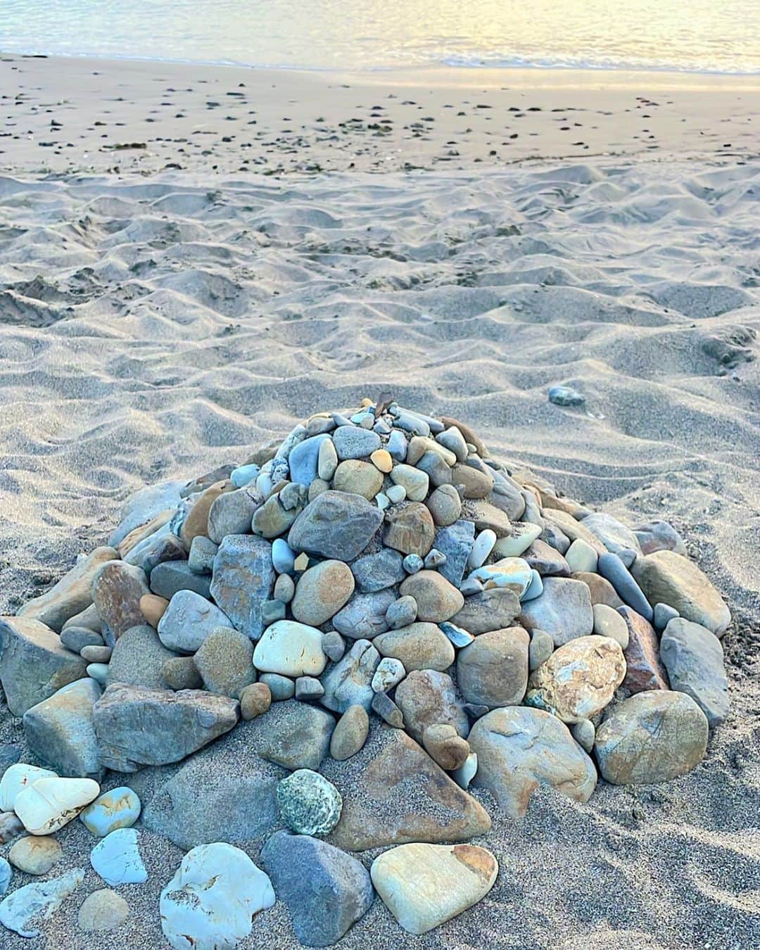 杉ありさのインスタグラム：「. とにかく"石""stone"に惹かれる2023年。  石は私たちの大大大先輩で 何千年何万年何億年の歴史があるものも。 ちなみに世界最古の石は約39億年前のものだそう!!👀  知れば知るほど奥深く、興味深い。  今年出逢った家にあるクリスタルも、この日に海辺で出逢った石も まぁるい気持ちにしてくれる…💎  そういえば私の座右の銘も "転がる石に苔は生えない" 石だ！😂  写真は海辺でパパと息子と一緒に作った作品🪨笑  いつか石を使ったお家に住んでみたい💭🩵」