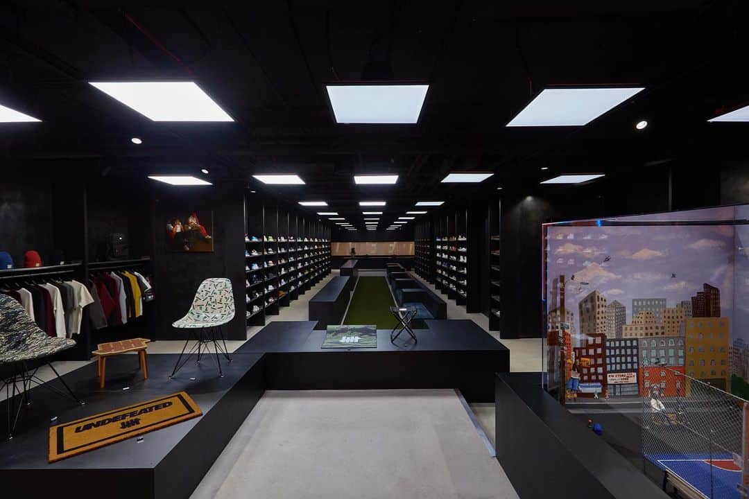 のインスタグラム：「UNDEFEATED New York  UNDEFEATED is humbled to announce the opening of its New York City Chapter store at 75 Kenmare Street. This is the first East Coast location for this Los Angeles-based brand and largest store footprint to date in the United States.  The store design was led by UNDEFEATED co-founder and co-owner James Bond in partnership with Schimenti Construction and is a matured take on the UNDEFEATED retail experience. The space includes dark-colored, Venetian-plastered walls, unique Richlite panels, stainless steel shelves and hang bars, custom millwork and stone-finished floors and a glass wall at the back of the store that features the iconic UNDEFEATED logo.  In addition to its highly curated product offering, the new location includes works from artists Alex Lujan, Clement Poplineau and Hely Gonzalez as part of its immersive experience, combining music, art and culture in a way that is authentic to the UNDEFEATED brand DNA.」