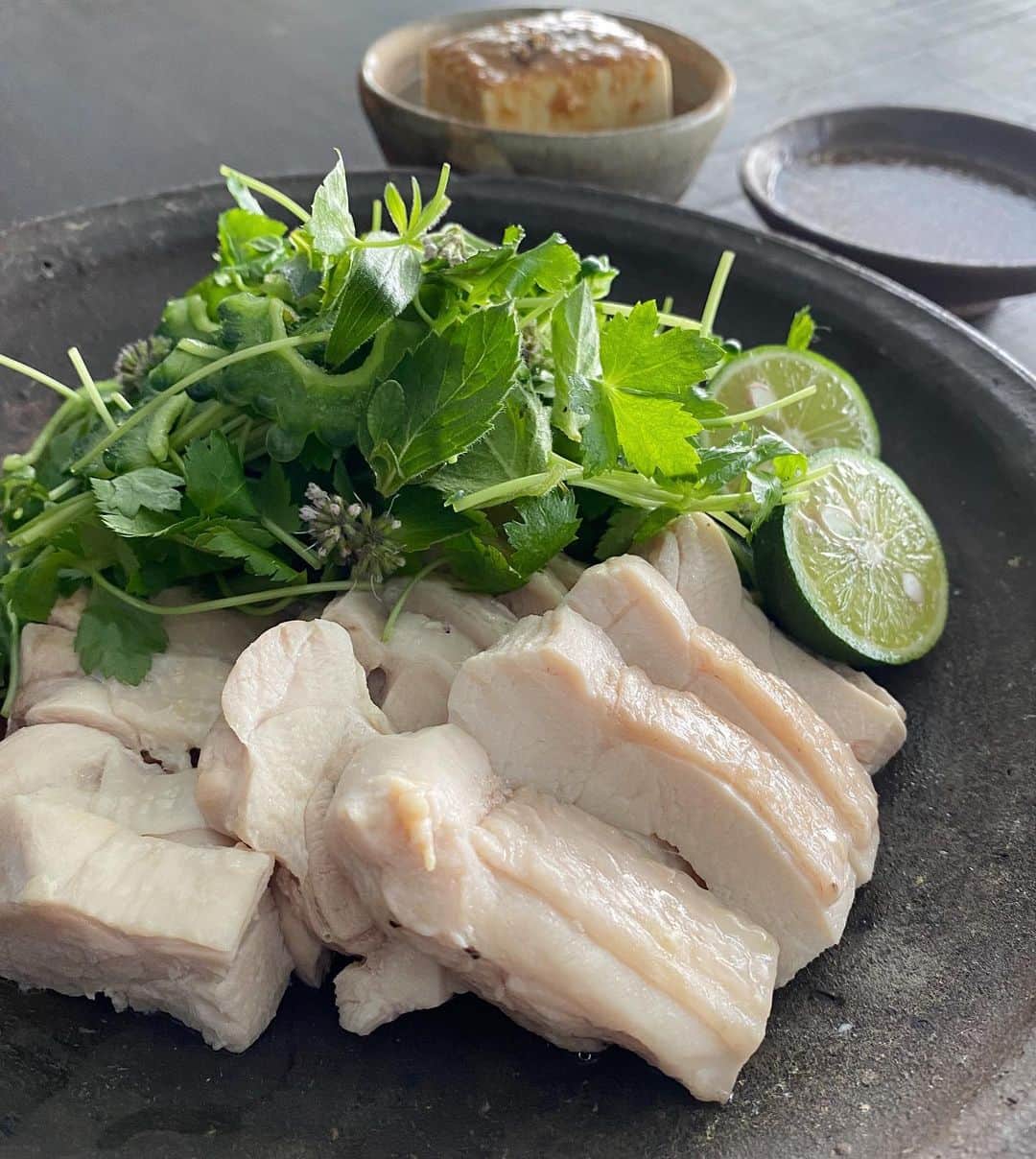 後藤しおりのインスタグラム：「週末の常駐型ケータリングのため、数日お弁当はお休みいただき、今日から仕込みです。  お昼の賄いは、蒸し鶏冷製、辛味冷奴、秋田のとんぶりをのせた玄米納豆ごはん、海藻の味噌汁。蒸し鶏にはシンプルな和え麺を合わせたいところ、今日は大好きな納豆ごはんも味噌汁も譲れず。鶏は塩をすり込み、酒と酢橘をたっぷり絞って蒸し、蒸した時に出た美味しいスープを使ってつけだれを。冷蔵庫に残っていた苦瓜や香草を添えて食べました。しっとり柔らか美味しくてうっかり食べ過ぎたので、午後からしっかり動きます。」