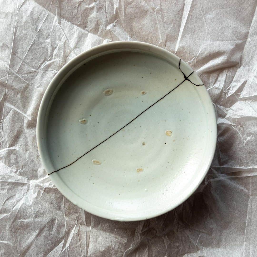 武井義明さんのインスタグラム写真 - (武井義明Instagram)「友人に頼んでいる器の修繕。「今回はね、ふふふ、金を使わずにやってみたの」……おお、漆継ぎ、黒がきれいだ！　見事にぱっかーんと割っちゃった鈴木大弓くんの皿だったけど、めっちゃかっこよくなりました。  @hiroyumisuzuki   In Japan, there is a method of repairing broken ceramics called "tsugi". Lacquer is used as the glue. Gold or silver powder is used as a finishing touch. This plate, which my friend spliced this time, was finished with lacquer. She decided that the black color was more beautiful because of the beautiful cracks. The process of "tsugi" is not just "repairing"; it is a process that brings out the individuality of the person who made the broken dish, and the broken dish is reborn as a new piece of art.」9月15日 9時30分 - bebechef