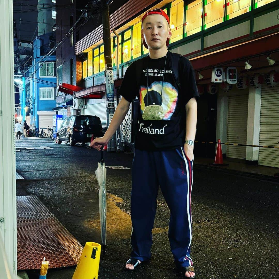 市川刺身さんのインスタグラム写真 - (市川刺身Instagram)「今日の服装。 朝から収録から人力舎さんの事務所ライブに出させていただく日。  ちょうど追っかけで一気に見たハヤブサ消防団にインスパイアを受けて皆既日食のTシャツ。 最高円寺のジャージ。 ヤンマーの赤帽子に黒の便所サンダルで金のがま口とmont-bellのメッシュリュック。 収録で帰りのタクシー出して頂いて乗ってる時に土砂降りの雨が降って到着した時も雨真っ盛りだったらタクシーの運転手さんが『ちょっと待ってね』と言って傘をくれました。 メッシュリュックなので助かりました。 無限大に荷物を取りに行った時にネルソンズの岸さんが『写真が1枚だと1枚かぁと思っちゃう』と言っていたので今日は2枚あげようと決めてたのですが撮れずで1枚の失態であります。 代わりといってはですが文字を多めにしました。 人力舎さんの事務所ライブに出させて頂いてとても楽しかったです。 また出させて頂きたいです。 高円寺に帰宅してきて道で携帯置いて撮りました。 振り絞って頑張ろう。 タクシーの運転手さん岸さん人力舎さんありがとうございます。  #今日着た服 #ファッション #古着 #タクシー #雨 #人力舎 #どっきん」9月15日 22時16分 - soitsudoitsu