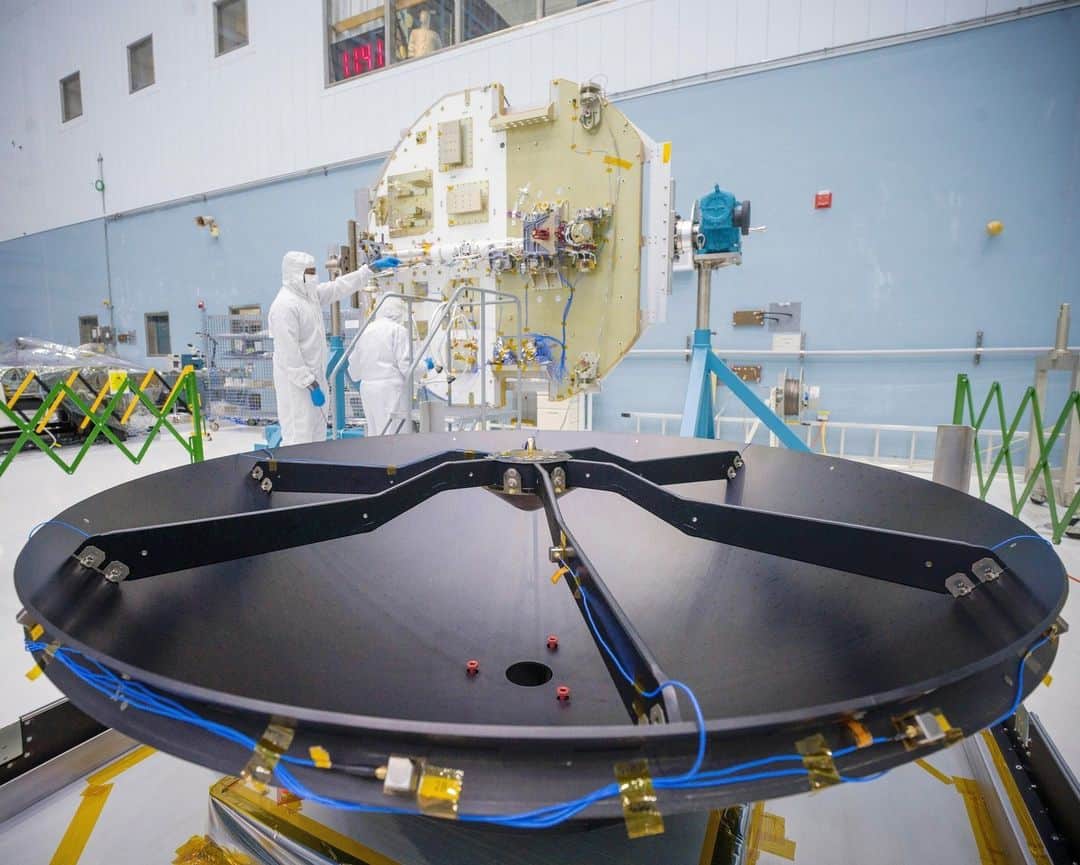NASAさんのインスタグラム写真 - (NASAInstagram)「What’s the dish! #ICYMI The Nancy Grace Roman Space Telescope's high-gain antenna system has been integrated onto the spacecraft’s communications panel in the Goddard clean room. The antenna will be able to send status updates of the spacecraft back to Earth, as well as up to 500 megabytes per second of data to ground systems across three different continents!   Photo Credit: NASA/ Chris Gunn  Image Description:  1: Wide shot inside the Goddard cleanroom. Two people in white head-to-toe suits with face coverings are holding a large black antenna dish. There are two people standing behind the dish but only their feet are visible.  To the left, there is a large gold round panel that is supported on a blue and grey stand. There is a silver beam that is laying flesh on the panel. 2: Side view of a large round black antenna dish in the foreground. There is blue wiring lining the outside of the dish. In the background is a large round panel standing upright. The panel is half gold and half white. There are square and rectangular boxes fused to the panel. There are two people standing in front of the panel in a white head-to-toe suit. They are examining one of the boxes on the panel.  3:Top view of the Roman communications panel, it is a large round and flat panel that is half gold and half white. There are small gold boxes welded to the panel.  There is a large black round antenna dish sitting on the gold side of the panel.  There is a person in a white head-to-toe suit and face covering to the top right of the panel. They have on blue gloves and are pointing at a wire that is attached to the panel.」9月15日 23時01分 - nasagoddard