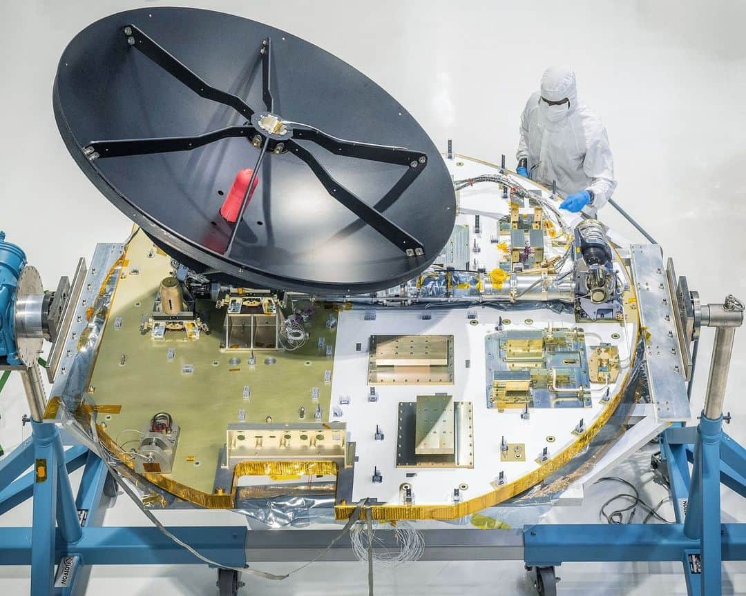NASAさんのインスタグラム写真 - (NASAInstagram)「What’s the dish! #ICYMI The Nancy Grace Roman Space Telescope's high-gain antenna system has been integrated onto the spacecraft’s communications panel in the Goddard clean room. The antenna will be able to send status updates of the spacecraft back to Earth, as well as up to 500 megabytes per second of data to ground systems across three different continents!   Photo Credit: NASA/ Chris Gunn  Image Description:  1: Wide shot inside the Goddard cleanroom. Two people in white head-to-toe suits with face coverings are holding a large black antenna dish. There are two people standing behind the dish but only their feet are visible.  To the left, there is a large gold round panel that is supported on a blue and grey stand. There is a silver beam that is laying flesh on the panel. 2: Side view of a large round black antenna dish in the foreground. There is blue wiring lining the outside of the dish. In the background is a large round panel standing upright. The panel is half gold and half white. There are square and rectangular boxes fused to the panel. There are two people standing in front of the panel in a white head-to-toe suit. They are examining one of the boxes on the panel.  3:Top view of the Roman communications panel, it is a large round and flat panel that is half gold and half white. There are small gold boxes welded to the panel.  There is a large black round antenna dish sitting on the gold side of the panel.  There is a person in a white head-to-toe suit and face covering to the top right of the panel. They have on blue gloves and are pointing at a wire that is attached to the panel.」9月15日 23時01分 - nasagoddard