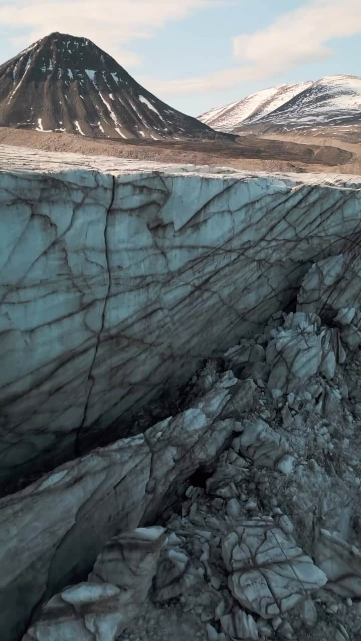 Explore Canadaのインスタグラム：「POV: You channel your inner penguin and dance with ancient ice giants in Nunavut, where 43% of the land is covered by glacier ice.        🎥: @phil.emond 📍: @destinationnunavut    #ExploreNunavut #SpiritOfTheArctic   Video description: Drone footage of various landscape views of mountain terrain, glacier edges and boats gliding through dark waters alongside the glacier.」