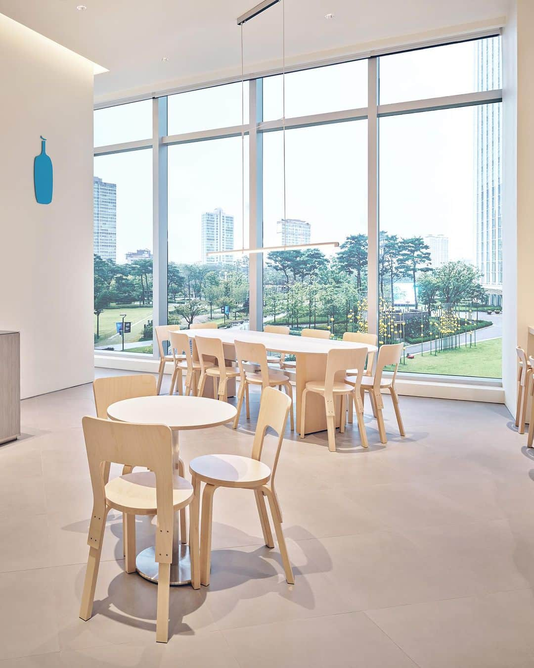 Blue Bottle Coffeeさんのインスタグラム写真 - (Blue Bottle CoffeeInstagram)「Introducing our 11th café in South Korea located at Jamsil Lotte World Tower, one of Korea’s most eye-catching and complex cultural structures. Lotte World Tower sustains both traditional and modern architectural features - the skyscraper embraces characteristics of traditional Korean objects while the tower itself is well-known for being one of the highest buildings in the world.  Our cafe design reflects the architecture of the tower itself. Since the tower was shaped like a traditional calligraphy brush, we incorporated many rounded details to match the tower’s uninterrupted curvature. From the bar area where the barista and guest first meet, to tables that encourage coffee and conversation, curved shapes are a central theme throughout.  Another important feature was to let natural sunlight cascade over the café. To accomplish this, many façades were incorporated into the design so guests could fully immerse themselves in the sunlight and the surrounding nature.  We look forward to welcoming you to our Jamsil Cafe.」9月19日 2時06分 - bluebottle