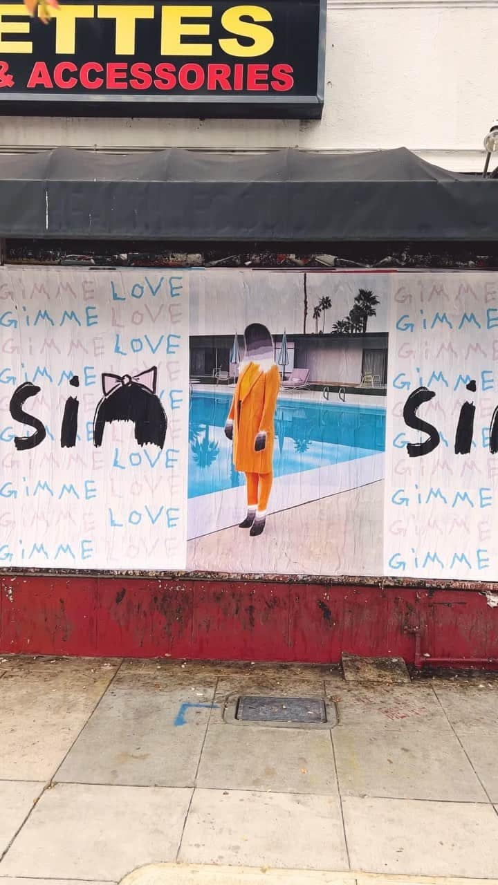 シーアのインスタグラム：「Spreading the love through LA! 🎬 Tag @siamusic if you see one in your city 💖 - Team Sia  [video description: a person stepping over a Sia “Gimme Love” stencil on a sidewalk, panning up to posters of the “Gimme Love” and ‘Reasonable Woman’ art, set to the song “Gimme Love”]」