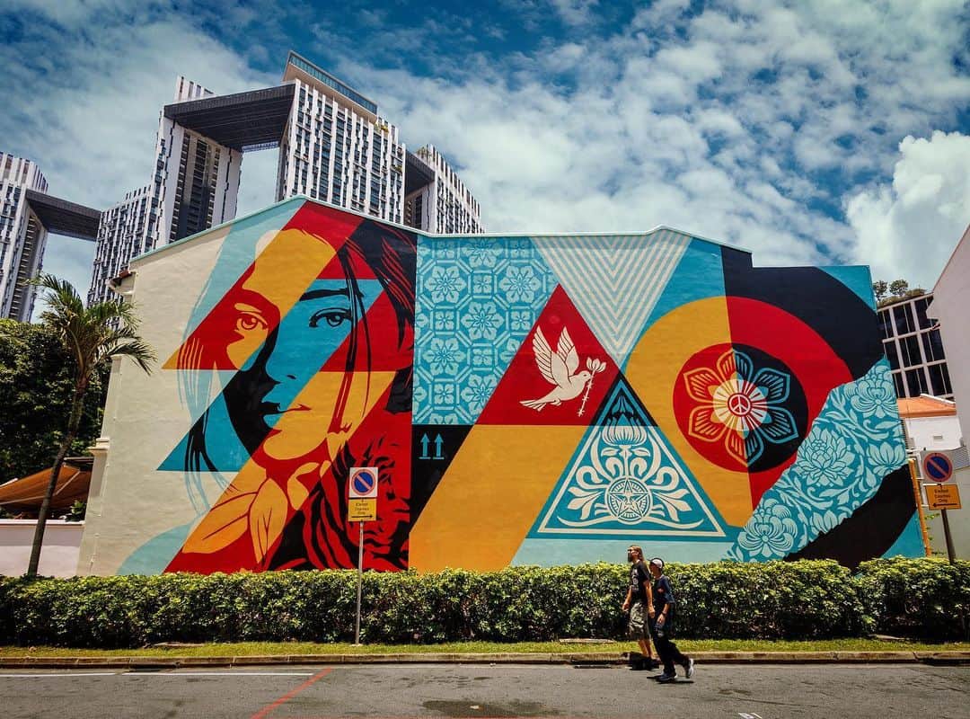 Shepard Faireyのインスタグラム：「The crew and I just returned from Singapore, where we painted a large mural called "Mosaic of Peace and Harmony." I did an art show at @operagallery with around 150 pieces and a pop-up clothing collab. Painting a mural is always important to me because I believe in the power of accessible art and the need for artistic expression in public spaces. I especially believe in these principles in a place like Singapore, which is very strict and bureaucratic, with more challenges to overcome to create public art. I'm very grateful to Opera Gallery for finding me an incredible wall in the Chinatown neighborhood and working for a year to secure the needed permits to make it happen. The next challenge was to find paint that I could use since Singapore does not carry MTN, my usual spray paint choice. In fact, Singapore only carries limited colors of water-based spray paint, which I applaud from an environmental standpoint, but it presents serious problems when working in 90% humidity conditions with unexpected bursts of rain! We also had to mix custom colors of latex paint to apply with rollers since our spray paint choices were limited. On top of the paint issues, the crew and I also had to complete a 9AM to 6PM safety training course to be permitted to work on scaffolding. We've painted over 125 large-scale murals with every sort of rig and safety measures, so it was frustrating to lose a day to a mandatory course, but hey, we're certified in Singapore now! Lastly, the execution of the mural was brutal for a few reasons, mostly that it was a sauna at 90 degrees and 90% humidity, but also because the humidity kept the water-based paint from drying, and the rain bursts would make the paint drip down the wall. We were all very drained by the conditions, but we finished after 4 days, and I'm happy with the result. Thanks to Dan Flores, Rob Zagula, and Jon Furlong (who also shot the great photos) for the hard work! Also, thanks to the @obey.asia / @obeyclothing crew and all the people who rolled by to say hello! -Shepard  Photo: @jonathanfurlong」