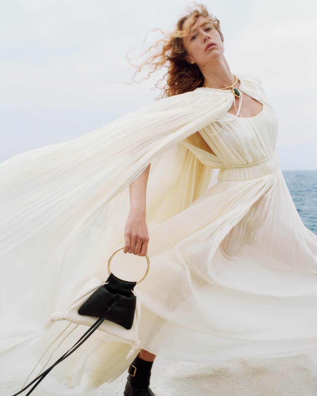 Chloéのインスタグラム：「Etesian winds of the Adriatic emphasise the featherlight quality of the ‘Eden white’ cape and long dress in pleated and gathered lower-impact wool gauze.  As seen on @raquel_zimmermann photographed by @zoeghertner for the #ChloeAW23 campaign.  Creative director: @gabrielahearst Art director: #PeterMiles Stylist: #CamillaNickerson」