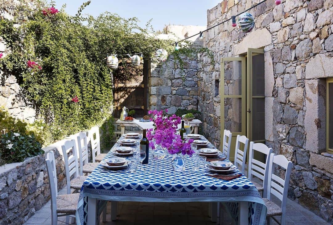 のインスタグラム：「One French fashion executive found her dream getaway on the Greek isle of Patmos. The house—fashioned from the ruins of a 17th-century stable— is almost completely surrounded by chapels and churches. “It’s like a stronghold,” she explains. “Nobody can see in from outside.” One of the property’s main draws is the garden. Getting it to grow, however, proved to be something of a headache, due to the rockiness of the land and the shortage of water. “It’s not like you can create a Provençal- or Hollywood-style garden here,” she says. After a certain amount of trial and error, she ended up coaxing it into life with lush and fragrant plants, such as jasmine and gardenias, junipers, pomegranate trees, lavender, bougainvillea, clipped laurel, and a Judas tree. The result, she says, is “just like a Perugino painting,” referring to the Italian Renaissance artist whose most famous pupil was Raphael. And, indeed, this alfresco dining patio is utterly picture-perfect.   Click the link in bio to tour this breezy Greek island retreat, as seen in the ELLE DECOR archive. Written by @iangphillips. Produced by @therobertrufino. Photographed by @bjornwallander.」