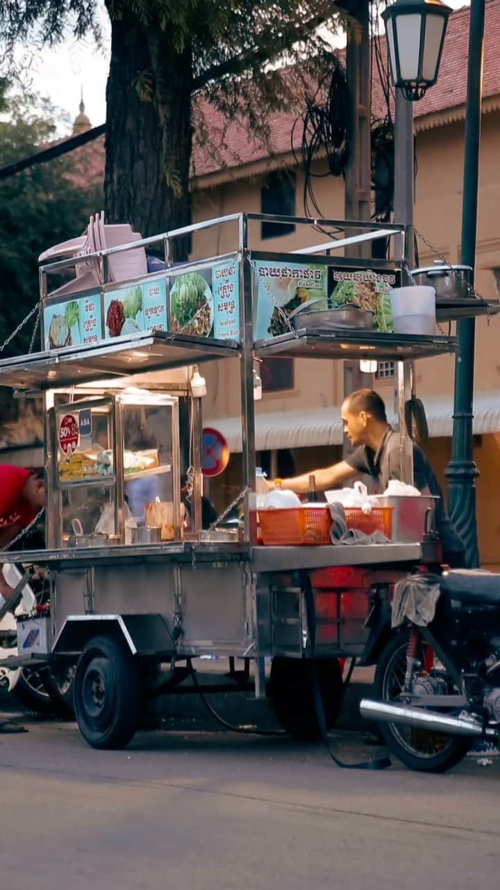 Shunsuke Miyatakeのインスタグラム：「Street vendor at twilight /   Various vendors are showing up on the street at twilight in Phnom Penh. They are turning on the light and preparing for the foods for customers at Wat Botum Park. They were chitchatting and smiling while cooking, that was beautiful for me.」