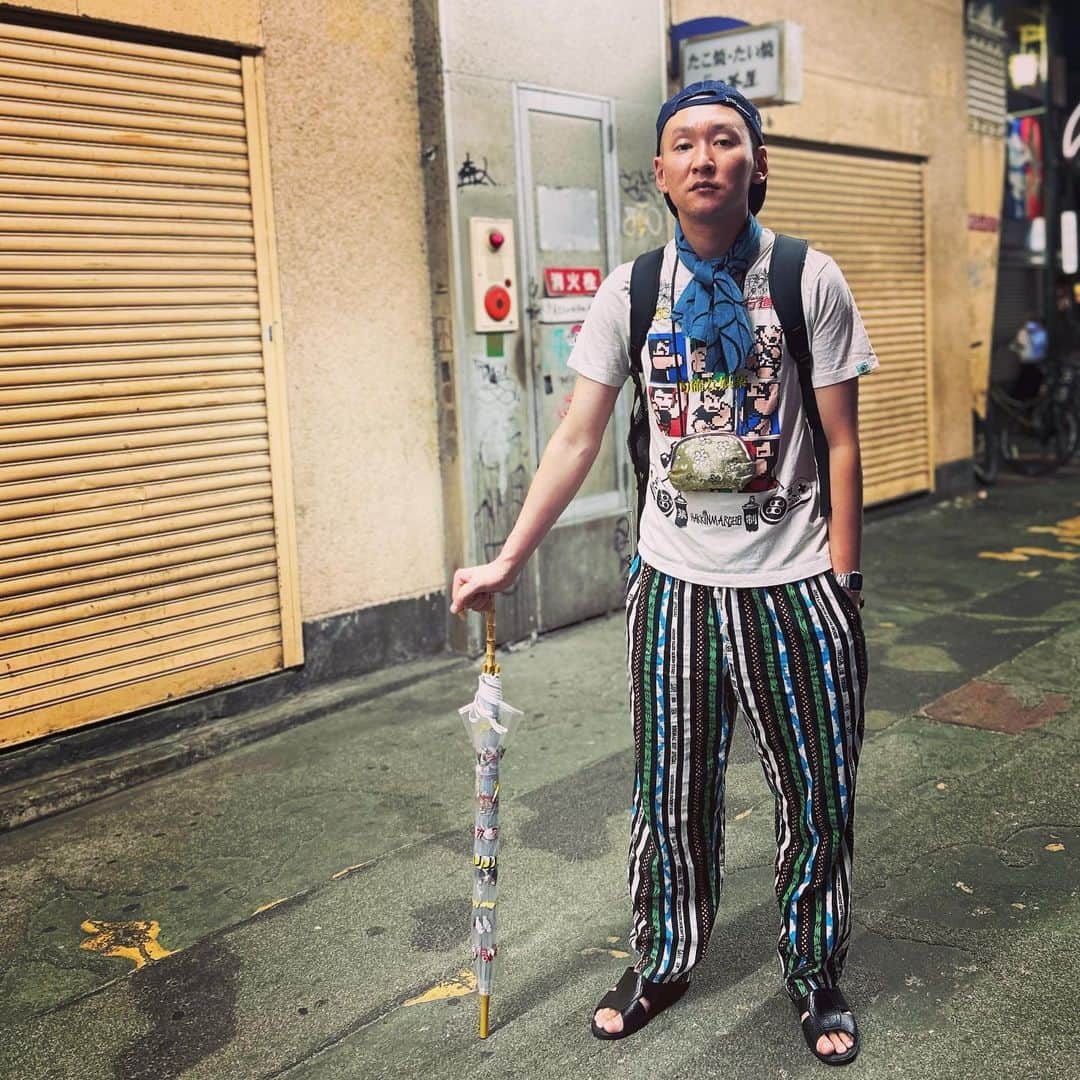 のインスタグラム：「今日の服装。 キングオブコント準決勝1日目の日。  くにおくんのTシャツ。 高円寺で購入したイージーパンツ。 JAのデニム地帽子に黒の便所サンダルで手ぬぐいと金のがま口にmont-bellのメッシュリュックで食べ物の傘。 キングオブコント準決勝1日目を終えて高円寺帰ってきて撮りました。 明日も全力で頑張ろう。 1日目ありがとう。  #今日着た服 #ファッション #古着 #高円寺 #キングオブコント #雨降らなかった」