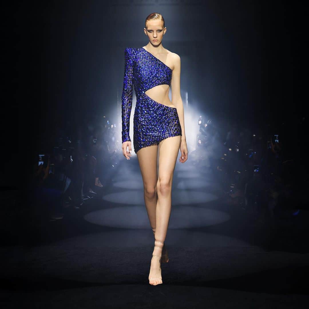 ジュリアンマクドナルドのインスタグラム：「An enchanting goddess graced the @JulienxGabriela runway in a daring asymmetrical drape gown with electric colbolt blue embossed Italian lame and embellished with thousands of sapphire blue Austrian crystals mixed with metallic shades of blue handmade circular metallic discs, finished with a signature statement power shoulder and daring thigh-high split from the @julienxgabriela AW24 collection  Big thank you to all who contributed to a successful JxG AW24 show  Styling: @karlplewka Makeup: @wendyrowe Hair: @sammcknight1 Nails: @glitterbels Shoes: @charkviani Belts: @jivomir.domoustchiev Tanning: @cocoandeve Production: @mybeautifulcity」