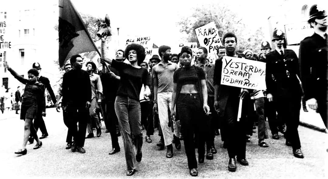 のインスタグラム：「From streetstyle to the Black Power movement, Sir Horace Ové was crucial in chronicling defining moments and figures at the forefront of change. He recorded the public and private lives of his community through powerful film and photography, blending drama and documentary.  In ‘Yesterday’s Dream, Tomorrow’s Reality’, we see a snapshot of a political rally from the front line in 1970. A distinct divide is seen between the white, uniformed police officers and the many Black activists. The artist would go on to say, ‘I've always been an active photographer. I live in a visual world. If there's anything going on socially or politically, I want to know about it. So the late 1960’s and early 70’s were a very busy time for me.’ After a long career, it is with great sadness we've received the news that Sir Horace Ové has died at the age of 86. He will be remembered for his trailblazing work.   📷 Horace Ové, Yesterday’s Dream, Tomorrow’s Reality: Barbara Beese Leading Demonstration, London 1970, printed 2021. Collection and © Courtesy Horace Ové Archives @horaceovearchives」