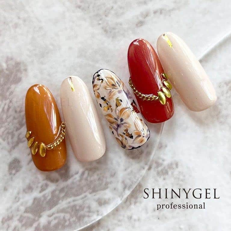 シャイニージェルのインスタグラム：「autumn nail 第1弾❤️  こっくりカラーも気になるこの季節🍂🍄🪹  キャメルとテラコッタカラーが 秋を感じさせるデザインです☺️  フラワーの配色も落ち着いた色味をチョイスしているところもポイント☝️  使用アイテム📝  ベースカラー #ella108 #ella096  フラワーアート部分🥀 #ella096 #ella107 #ella108 #ella122  #ella137 #nova1060 #アートジェルブラック #アートジェルホワイト  #ck_デザインパーツセットa  #ruyiya_チェーン889 #ck_ホイルフレーク  @shinygel SHINYGEL PRO SHOP（プロ向け） シャイニージェル公式ショップ（一般向け）  ＊＊＊＊＊＊＊＊＊＊＊＊＊＊＊＊  シャイニージェルとは ━━━━━━━━━━  ★爪を傷めない弱酸性  ★オフ後も爪がしっとり  ★純国産のこだわり  「安全で爪を傷めない確かなジェルをお届けしたい」  そんな想いからブランドが誕生しました。 化学的根拠に基づいて「爪に優しい」を研究し、 時代に合ったより良い安全な製品をお届けできるよう 製品の改良と新製品の開発を行っています。  ＊＊＊＊＊＊＊＊＊＊＊＊＊＊＊＊  パワーベース認定サロン募集中！！ ━━━━━━━━━━━━━━━━  パワーベース認定サロンとは？  パワーベースを導入しているサロンのうち、製品特長をしっかりと理解し正しい技術で施術サービスを提供できるとを当社が公式に認めたサロンだけが認定されます。  詳細が気になる方、お申し込みを希望される方はDM📩で詳細をお送りいたしますのでご連絡ください。  #シャイニージェル #shinygel #爪を傷めないジェルネイル #爪を傷めないジェル #弱酸性ジェルネイル #弱酸性ジェル #ネイルアート #ジェルネイル #秋ネイル#秋ネイル2023#フラワーネイル」