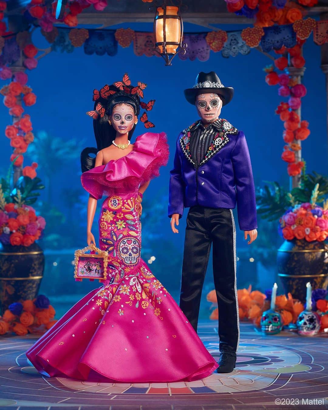 Mattelのインスタグラム：「@Barbie is marking the fifth year of the #Barbie Día de Muertos collection, by honoring the spirit of the upcoming Mexican festival of remembrance with newly unveiled designs paying homage to its customs and symbols. 🕯️   This year, Barbie wears a beautiful satin pink gown with vibrant calavera and floral embellishments, a crown of symbolic monarch butterflies float around her, and she carries a miniature ofrenda diorama with traditional cempasúchil accents. Ken wears a striking dark blue jacket with intricately embroidered lapels, a metallic striped shirt, a hat with silver detailing, and sleek black boots. Both Barbie and Ken wear traditional sugar skull face paint.   May the 2023 #DiaDeMuertos Barbie and Ken dolls become a treasured part of your holiday tradition.   #HispanicHeritageMonth」