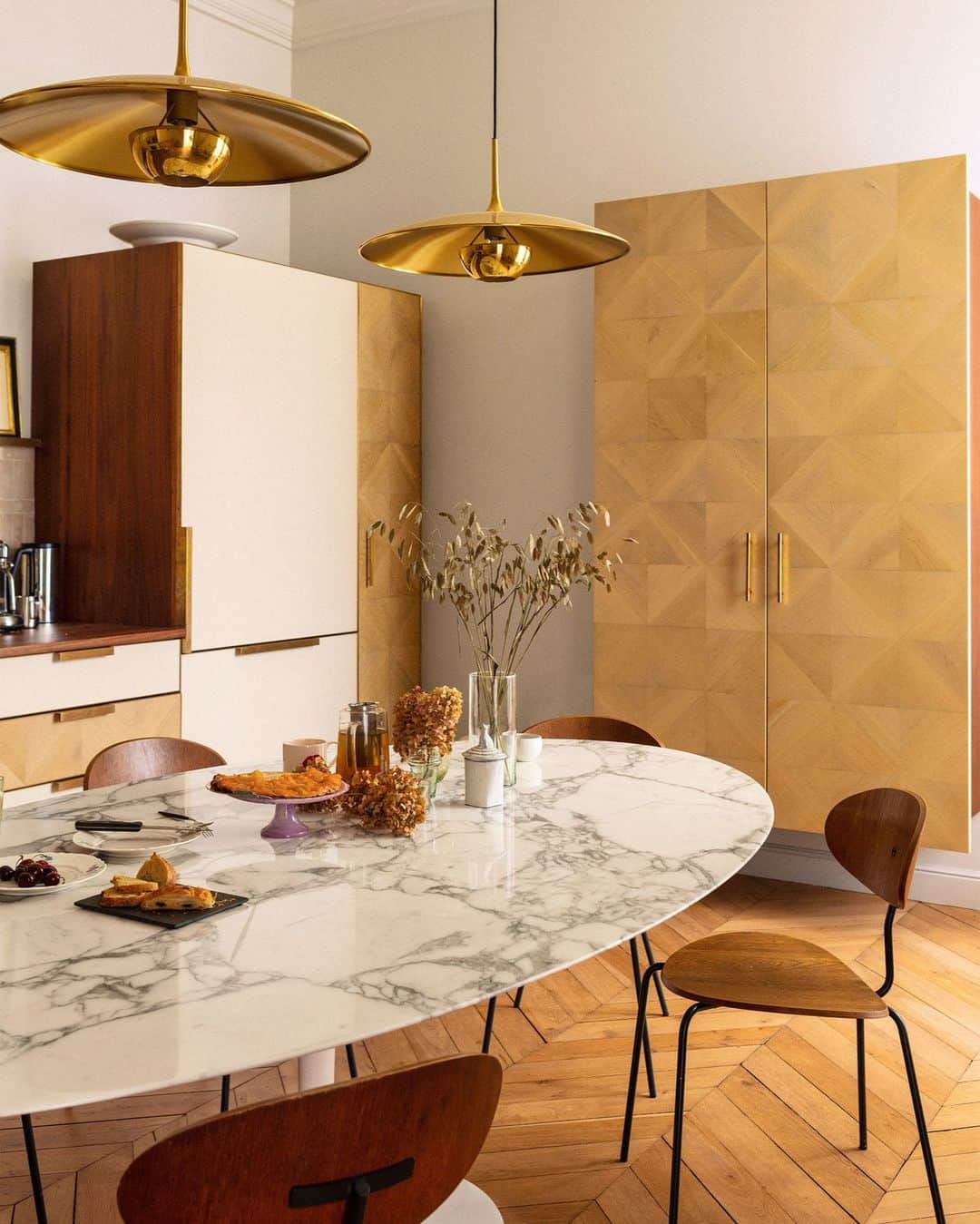 のインスタグラム：「In this Parisian kitchen, it’s hard to tell what’s old—and what’s older. Retrouvius’s (@retrouvius) Adam Hills regularly gets phone calls from people with a bizarre breadth of what they want to dispose of—paneling, or display cabinets, or a set of doors, or amazing old floors, or 200 lights. “Really random,” says Maria Speake, who works alongside him. “And that’s where the fun comes in.” Here, the kitchen got a timeless upgrade in the form of cabinet doors made from salvaged oak parquet floors, vintage French school chairs, and a Saarinen table for @knoll.  Click the link in bio for the full tour of this Paris Triplex, as featured in our October 2023 Change Issue. Written by @danathomasparis. Photographed by @theotennant1.」