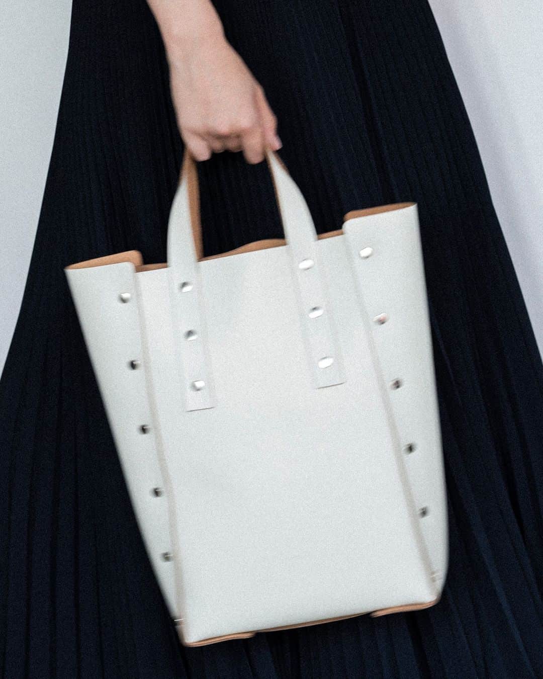 エンダースキーマのインスタグラム：「“assemble” assemble hand bag tall M  “assemble” is a collection of leather items that are 'assembled' and formed by riveting leather patterns, without sewing processes, like making a plastic model kit.  The simple, unlined structure gives the products a more minimal look and highlights the natural color of the interior cowhide against the gloss leather exterior.  #assemble #henderscheme #2023sa」