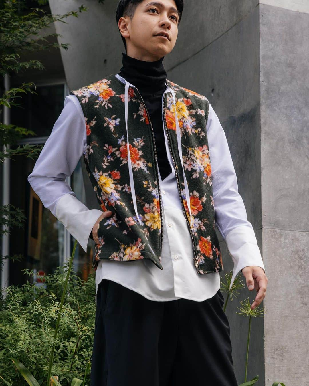 ノアファーのインスタグラム：「23AW Mens flower zip wool vest ブラックベースに花柄が目を惹く、暗めになりがちな秋冬コーデのアクセントになってくれるウールベスト。 着てみると見た目以上にすんなりマッチしてくれるのは、首元がクルーネックだったり、フロントがジップになっていたり、ストンとしたボックス型のシルエットだったり細かいディテールにこだわっているから。 メンズでも似合うようにこだわってデザインした1着。  #noirfr #23aw」