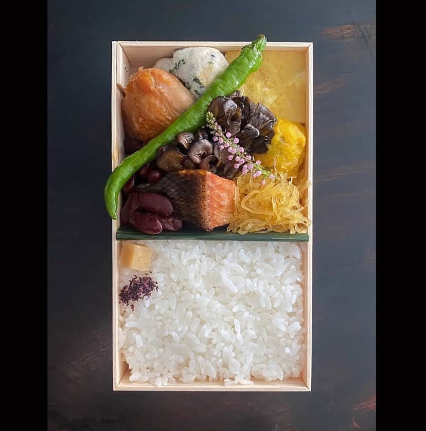 後藤しおりのインスタグラム：「定休日ですがイレギュラー営業で土鍋ごはん弁当・七寸、ぼだっこ海苔弁当の出荷でした。切るか、切らぬか、一瞬悩んでそのまま丸ごと一本入れたら、少し大きすぎた万願寺とうがらし。暑さが和らいで過ごしやすくなってきたので、金時豆蜜煮も入りました。裏庭の紫蘇の花が咲き始めましたよーと季節のお知らせも添えて。  朝の冷たい空気があまりにも気持ち良く、身体中におもいっきり吸い込み、幸せに包まれ出勤。秋が好きすぎてたまらない。」