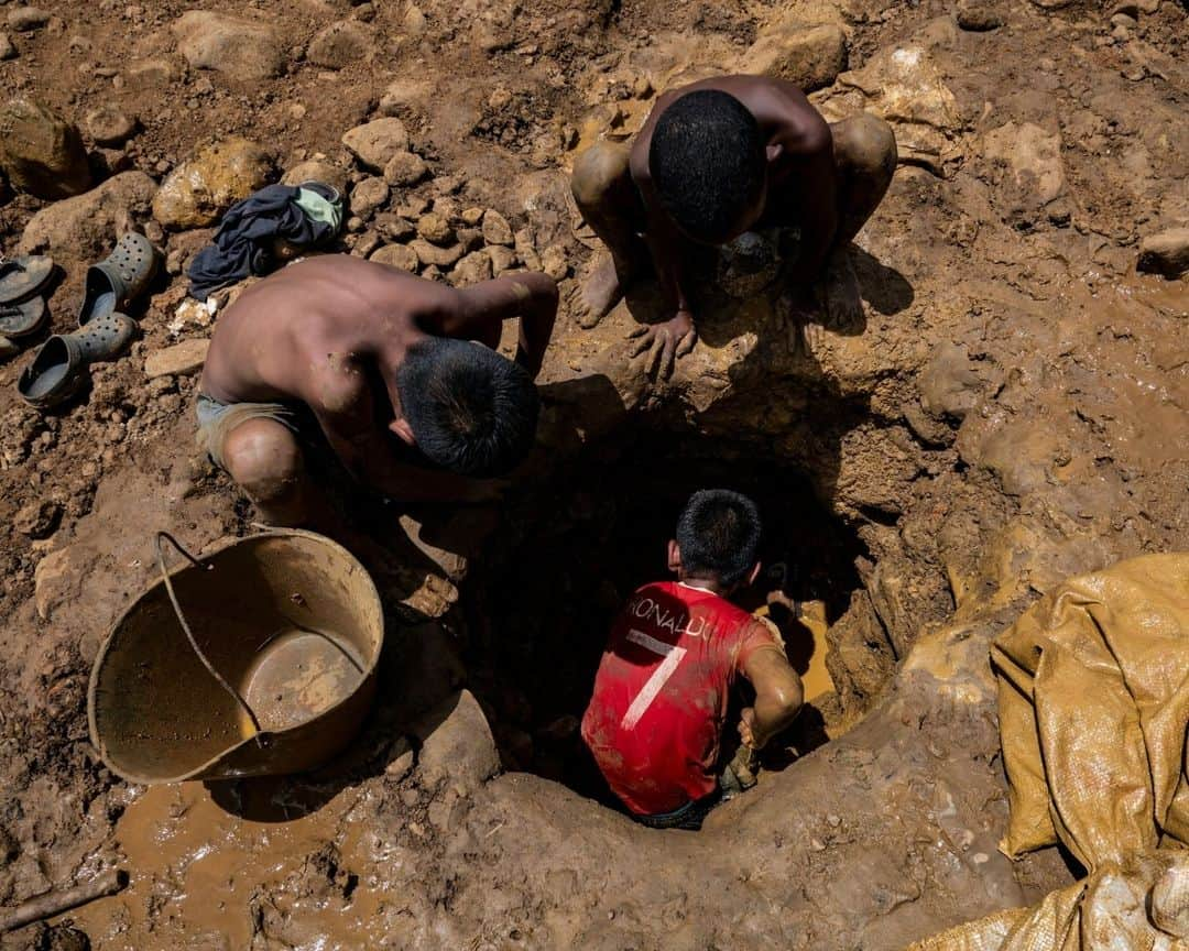 AFP通信さんのインスタグラム写真 - (AFP通信Instagram)「Gold and mercury, not books, for Venezuela's child miners⁣ ⁣ In the Venezuelan town of El Callao, extracting gold from soil starts as a kid's game, but soon becomes a full-time job that human rights activists slam as dangerous exploitation.⁣ Small and agile, the children's size helps them shimmy into narrow wells to hack out muddy earth, hoping it will contain gold -- which has become ever more precious as Venezuela's oil production has plummeted⁣ ⁣ 1 - A miner wearing a shirt with the image of "Uncle Sam" digs in a mine to extract gold, which will then be sold in El Callao, Bolivar State, Venezuela.⁣ ⁣ 2 - A miner works with a bar to dig and extract gold.⁣ ⁣ 3 - A miner shows rocks with traces of gold found in a mine to later be processed by hand in a mill in El Callao.⁣ ⁣ 4 & 5 - Mining children work digging in a mine in search of gold.⁣ ⁣ 6 - A young miner carries a bag of mud in an open pit mine in search of gold to later sell it in El Callao.⁣ ⁣ 7 - A mining boy unloads a bag of mud into a wooden container used to strain and wash mud in search of gold.⁣ ⁣ 8-> 9 - A young  miner strains and separates mercury from the mud used to adhere gold found in an open pit mine⁣ ⁣ 10 - A mining boy shows a ball of mercury that is used daily to separate the gold found among mud puddles.⁣ ⁣ 📷 @magdagibelli⁣ 📷 @yrispaul_21⁣ #AFP」9月24日 20時00分 - afpphoto