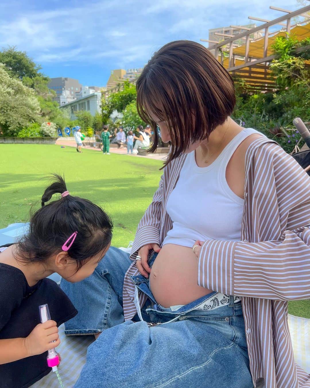 伊藤ニーナのインスタグラム：「公共の場でまんまるお腹丸出しでごめんね🤣 かわい子ちゃんの『おなか見せてーっ👧💖』には全力で答えたい🥹  #ピクニック日和 ♡ #ネイルとお洋服マッチ 💅 #バイキンマンシール全部プレゼントしてくれた #いよいよ着れる服が少なくなってきたﾖ #にーなのしふく」