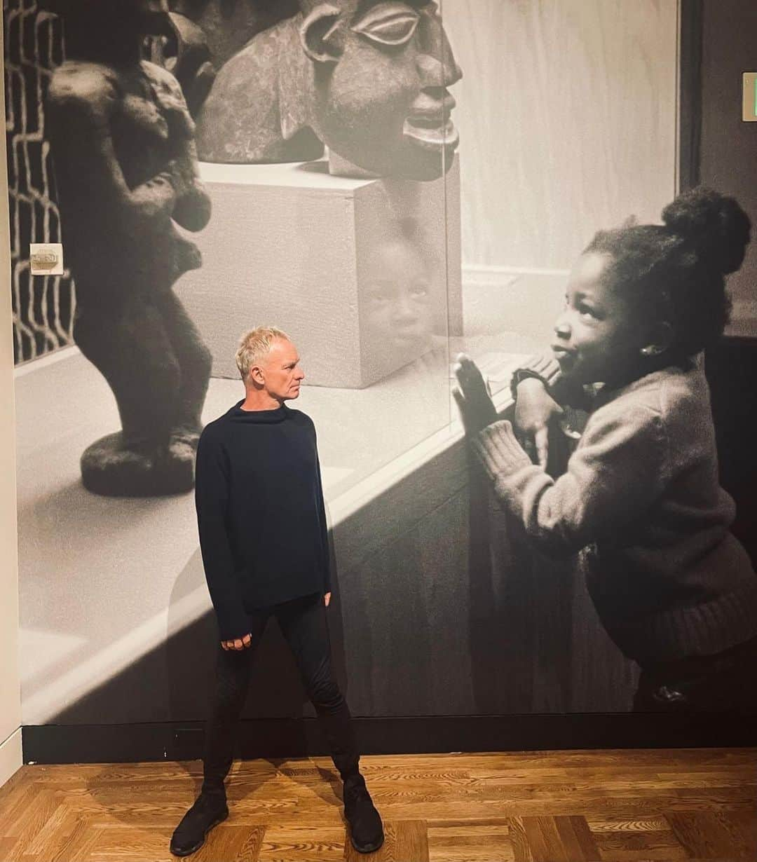 スティングのインスタグラム：「#Repost @portlandartmuseum ・・・ 🎶 Every breath you take, every move you make…  We were honored to welcome 17-time Grammy-winning recording artist @TheOfficialSting who stopped by on his My Songs World Tour to visit “Black Artists of Oregon” at the Portland Art Museum. The exhibition is on view through March 17.  Thanks for stopping by!  [ID: Photo of Sting standing in front of photomural by Richard Brown of a young girl looking at casework with art.]」