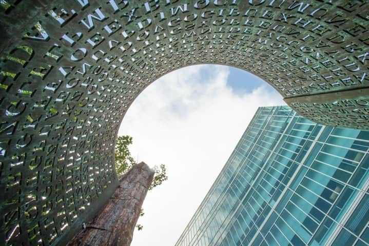 CIAのインスタグラム：「This sculpture on #CIA's campus, titled "Kryptos," is somewhat of a mystery and challenge to Agency employees.    With a theme of "intelligence gathering," the artwork is composed of petrified wood and a large S-shaped copper screen that looks like a piece of paper coming out of a computer printer. Inscribed on the “paper” are several enigmatic messages, each written in a different code.    #LookAtLangley #PhotoOps」