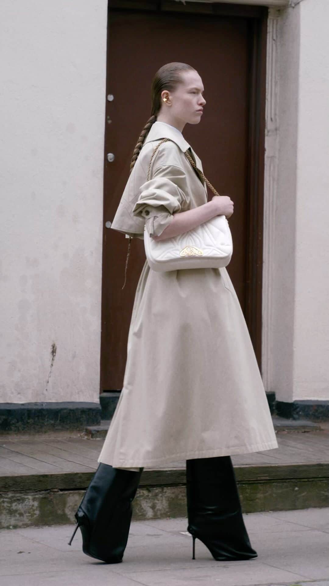 アレキサンダー・マックイーンのインスタグラム：「A cocoon sleeve trench coat in beige cotton gabardine with black heeled trousers and the ivory #McQueenSeal bag.  Discover the #McQueenAW23 collection via the link in bio.  Video by @EbbaHult Track: Neurons by @roblewiscomposer Music Director: John Gosling」