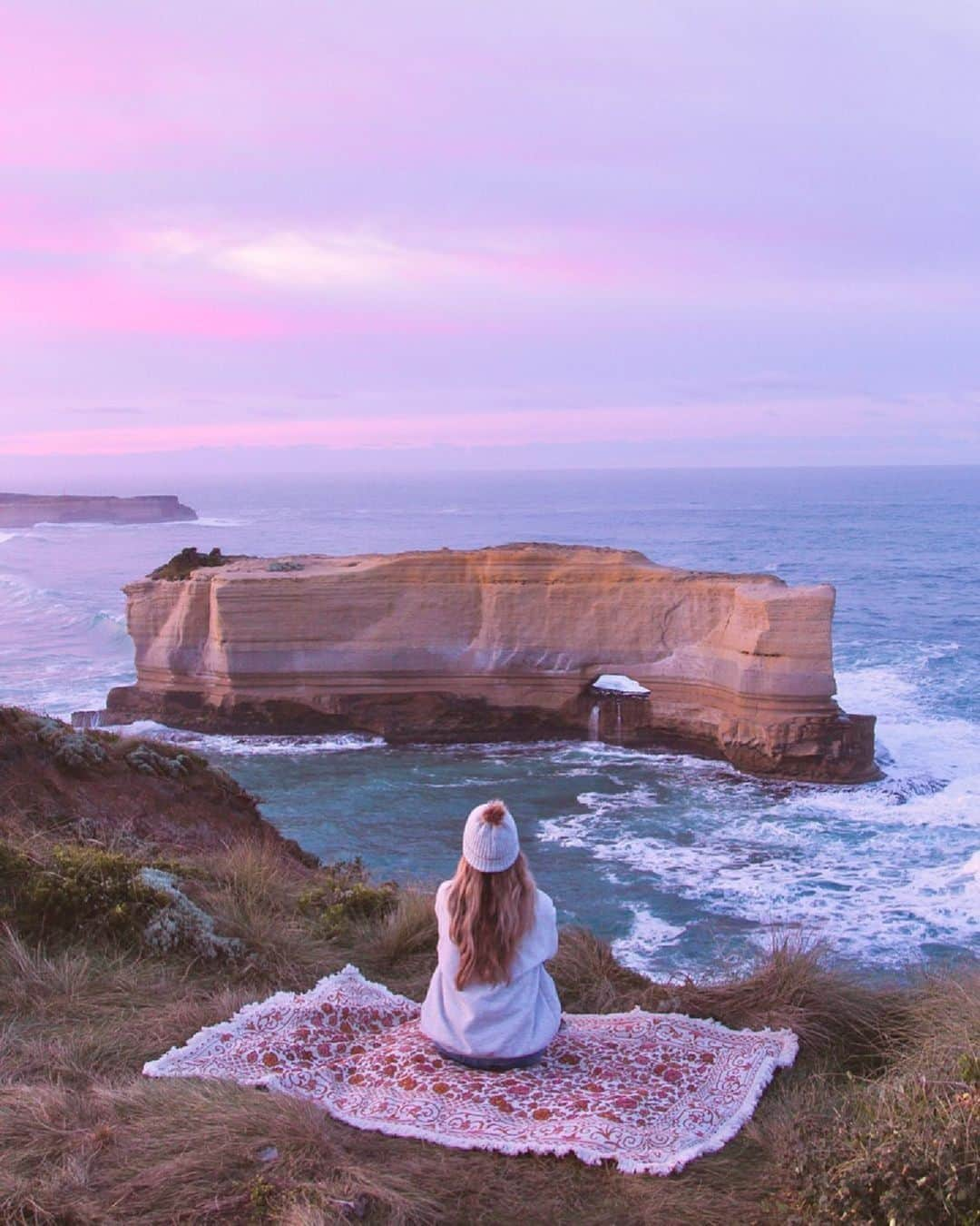 Australiaさんのインスタグラム写真 - (AustraliaInstagram)「Sunrises hit different along the @visitgreatoceanroad 💜🌊 @taylorcoooper captured our new favourite picnic spot on #Victoria's gorgeous coastline, and there's plenty more where that came from on especially when #roadtripping along this iconic coastal drive 🚗 Think sunset picnics at the limestone stacks of the @visit12apostles, #TheBakersOven (yep, just like this ☝️) or on the sandy stretch of #LochArdGorge 🏖️ If restaurant dining is more your style, be sure to check out @chrissbeaconpoint for incredible views paired with mouthwatering meals.   #SeeAustralia #ComeAndSayGday #VisitVictoria #GreatOceanRoad #Greatopia  ID: A woman seated on a picnic blanket overlooking the ocean, with waves crashing against a limestone formation at The Bakers Oven.」10月25日 18時00分 - australia