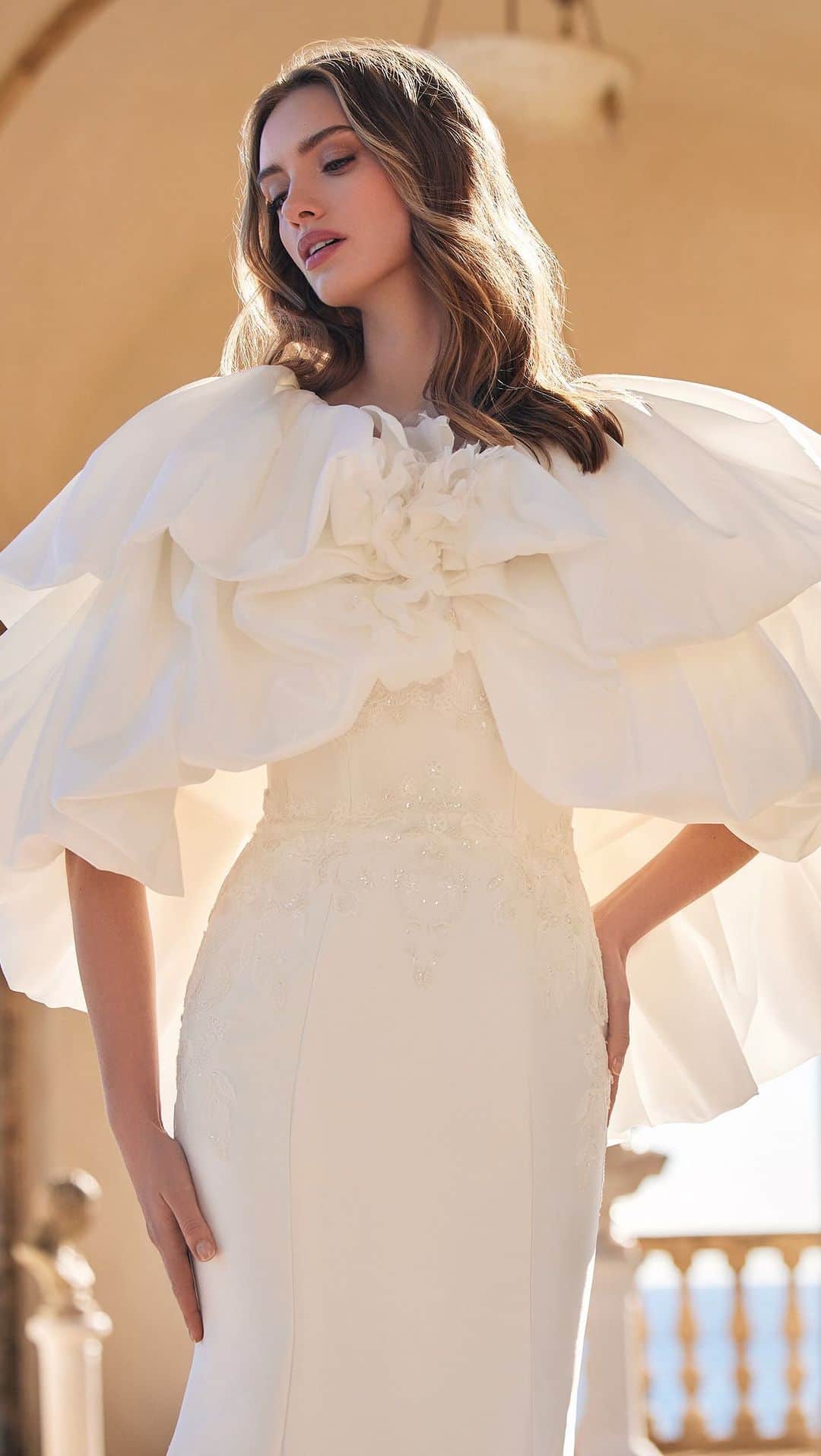 Pronoviasのインスタグラム：「Crown yourself the protagonist of your story💛 The voluminous cape will elevate your total look with timeless elegance.   Dress: Hecate  Discover our #Olympia collection in stores ✨  @marchesafashion @marchesabridal   #MarchesaForPronovias」