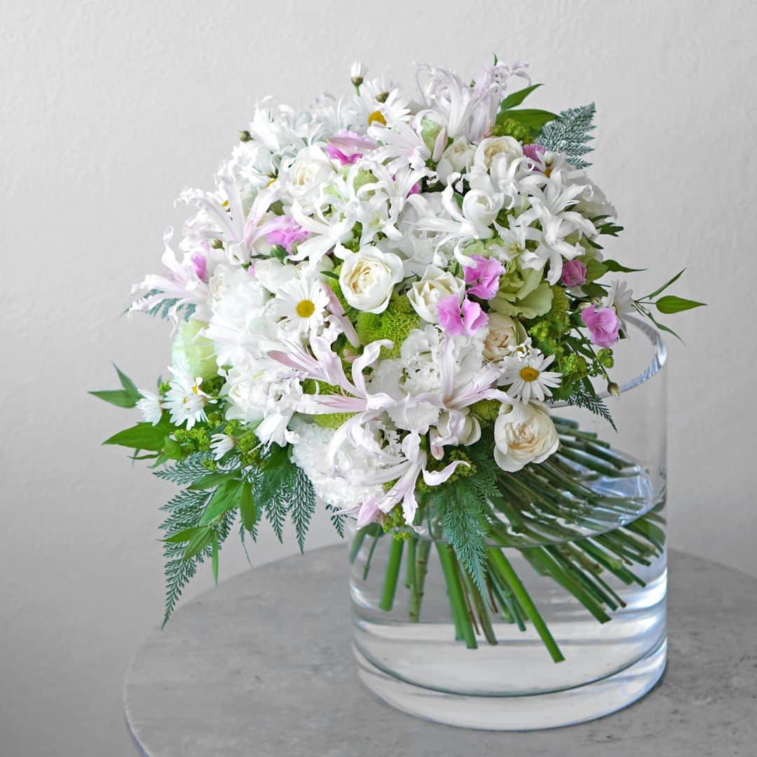 AOYAMA_HANAMOさんのインスタグラム写真 - (AOYAMA_HANAMOInstagram)「重なり合う花々の繊細な美しさに魅せられて。 ・ くるりとカールした花びらが愛らしい淡いピンクと白のネリネ、白いスプレーバラやマーガレット、淡いグリーンのスプレーマムやトルコキキョウ、ピンクのナデシコなど。優しい色彩の花々をふんわりとまとめ、柔らかな印象に仕上げました。 細やかな花々が重なり合って、まるで花畑のようなにぎわいを感じるブーケです。 ・ ネリネという名前は、ギリシャ神話に登場する水の妖精「ネーレーイス」が由来になっています。太陽光を浴びてキラキラと輝く姿が、女神・ネーレーイスに匹敵するくらい美しいとされて名付けられたのだそうです。 今回使用したネリネはボーデニー系という品種群ですが、サルニエンシス系という品種群は特に存在感のある輝きを放ち、別名「ダイヤモンドリリー」と呼ばれています。 ・ ネリネがもっとも美しく咲く時期は10月〜12月。ぜひ、皆さまも旬を迎えたネリネをお楽しみください。 - - - #aoyamahanamo #青山花茂 #お花のある生活 #花が好きな人と繋がりたい #花を飾ろう #花のある暮らし #花のあるくらし #花のある日常 #癒しの花 #季節の花 #旬の花 #花とおうち時間 #花贈り #フラワーギフト #花の贈り物 #ネリネ #ナデシコ #スプレーバラ #スプレーマム #トルコキキョウ #マーガレット #オーダーメイドブーケ #青山花茂おまかせブーケ #花束 #ブーケ #ネリネの花束 #ナチュラルブーケ #ウエディングブーケ #クラッチブーケ」10月26日 18時00分 - aoyama_hanamo