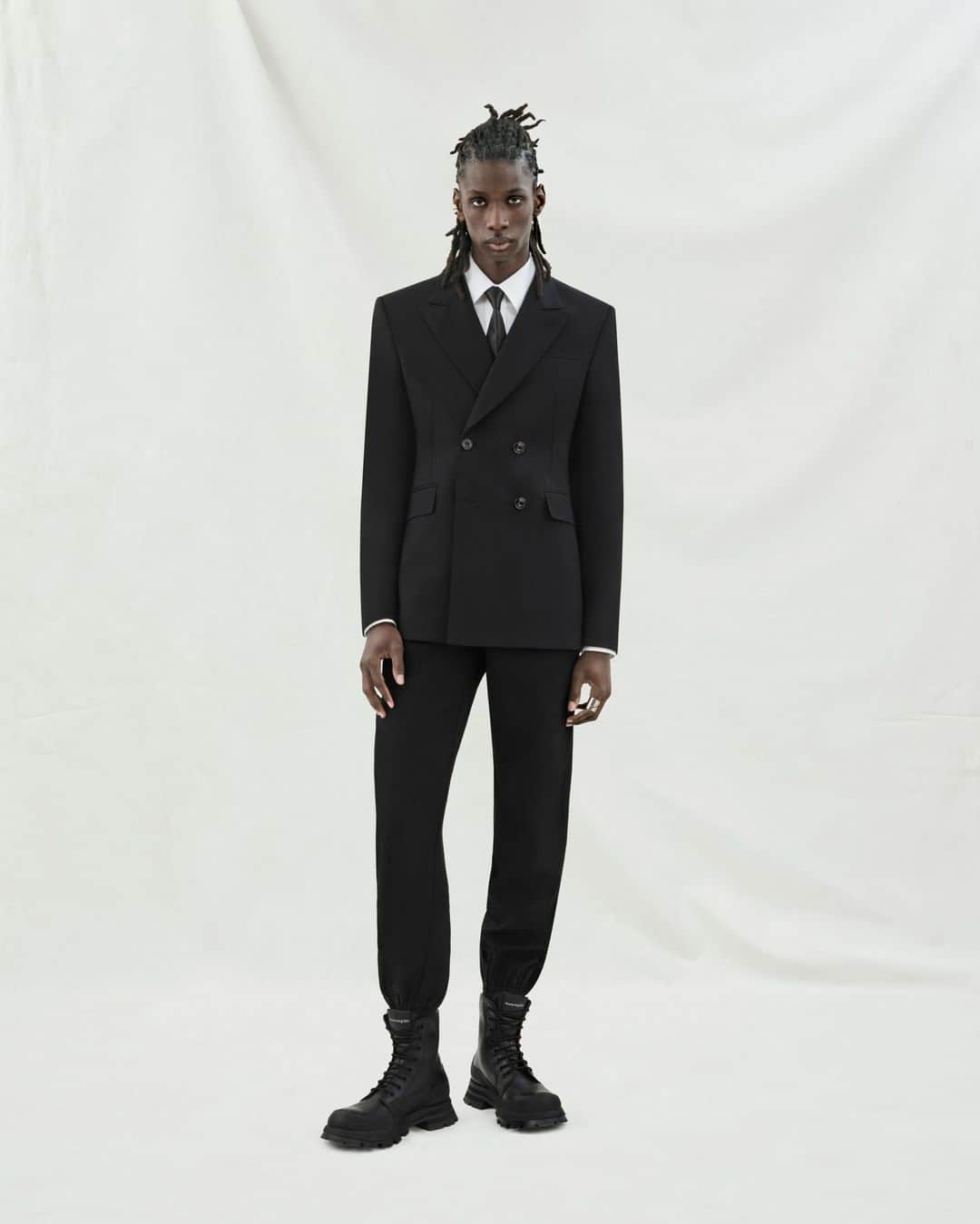 アレキサンダー・マックイーンのインスタグラム：「A double-breasted tailored jacket and cargo trousers in black, worn with a white shirt and a black tie.⁣ ⁣ Discover the new #McQueenMenPreSS24 collection via the link in bio.⁣ ⁣ Photographed by @Jet.Swan ⁣ Video by @EbbaHult ⁣ Track: Indigo by Hit By A Rock⁣ Music Director: John Gosling」