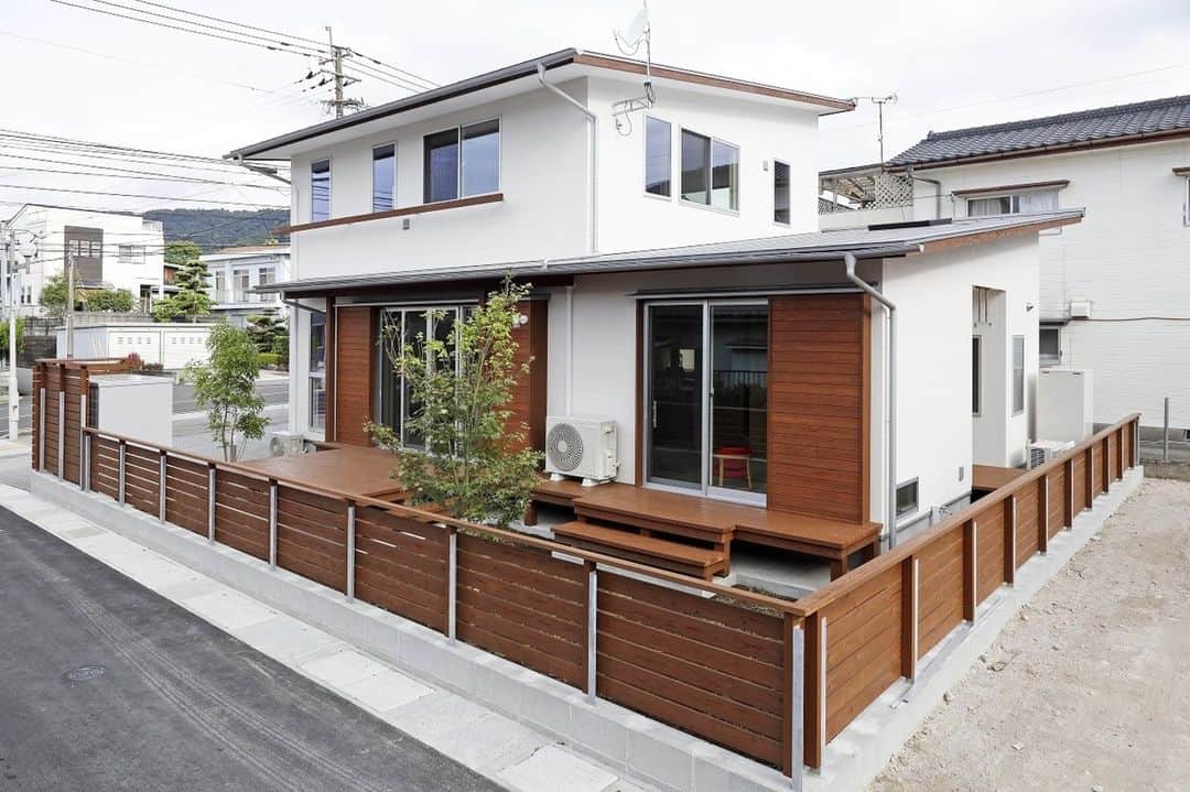 Yasuhiro Arimuraのインスタグラム：「白を基調とし、木の質感を同じにした外観。 塀とウッドデッキ、雨樋など細かなところまで同じ質感と色にしてあるので、まとまってスッキリとした印象。 家の背部には、洗濯物を干せるサンルーム的なスペースを設けています。  植物は苦手という方は結構いらっしゃいます。しかし、1本植えてあるだけで、家の雰囲気はがらりと変わりますよ。 季節の移り変わりがわかる植栽だったら、庭を眺めて四季を感じることもできますね。 お手入れがあまり必要ないものもあるので、探してみてはいかがでしょうか。  植栽を植えるポイント。人の目を楽しませる目的か、防犯面やプライバシーの確保が目的なのかによって、植栽選びは変わってきます。 どのくらいまで成長するサイズのものを、どの場所にどの向きで植えるのか、そこまで考えて計画するとオシャレな外観に。  more photos... 👉 @yasuhiro.arimura #光と風 #sumais #リビング #明るいリビング #注文住宅 #家づくり #2階建てのお家 #造作建具 #ウッドデッキ #マイホーム #マイホーム計画 #木の家 #住まい #新築 #オーダーメイド住宅 #鹿児島 #工務店 #工務店がつくる家 #工務店だからつくれる家 #設計事務所 #子育て #自然素材 #賃挽き製材 #デザイン #暮らし #暮らしを楽しむ #シンプルな暮らし #丁寧な暮らし #田舎暮らし #instahouse」