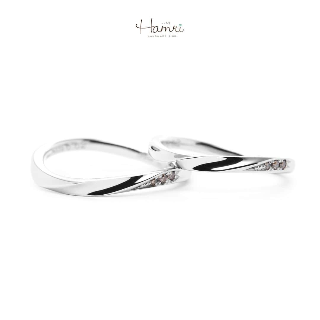 結婚指輪・婚約指輪『Hamri(ハムリ)』のインスタグラム：「【ふたひねりの指輪をご紹介です】  お手元を綺麗に魅せてくれる、細身のウェーブをベースに ふたひねりを加えたデザインです。 サイドお留めした3石のブラウンダイヤモンドが 控えめながらもお手元を華やかに彩ります♡  内側にはお二人のお名前と記念日 桜のモチーフがレーザーで刻印され、 お二人のこだわりが詰まった素敵な指輪が完成いたしました！ ご結婚おめでとうございます！  💓ふたりらしい指輪と想い出を💓 @hamri_omotesando ==========================  ♦︎♢作成中の写真や動画を撮影、全データプレゼント♢♦︎  DMやLINEでのご相談お待ちしております♥ ⇒@hamri_omotesando  ❁・❁・❁・❁・❁・❁・❁・❁・❁・❁・❁  ＊セットリング5%OFF＊  @hamri_omotesando  Hamri「ハムリ」  〒150-0001 東京都渋谷区神宮前5-11-11 2F  tel 0120-121-175 hp https://hamri.jp/  open 11:00〜19:00 close 火/水　祝日営業  ❁・❁・❁・❁・❁・❁・❁・❁・❁・❁・❁  #手作り結婚指輪 #手作り婚約指輪 #結婚指輪#マリッジリング #エンゲージリング #プレ花嫁 #Hamri #Hamri表参道 #オーダーメイドリング #鋳造 #ブライダルリング #ペアリング #鎚目リング #プラチナリング #ピンクゴールド #シャンパンゴールド #ゴールドリング #コンビネーションリング #2023wedding #2023春婚 #2023夏婚 #プレ花嫁準備 #プレ花嫁と繋がりたい #結婚指輪探し #結婚指輪選び #結婚準備  《Hamri検索タグ》  #hamriデザイン #hamri指輪作り #hamri花嫁」