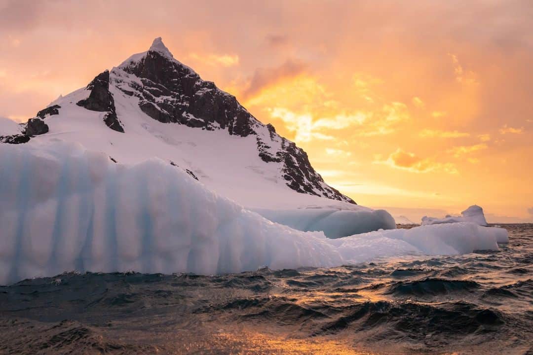 National Geographic Travelのインスタグラム：「Photo by @daisygilardini | During one of my recent expeditions to Antarctica, we decided to put the Zodiac in the water late—at 10 p.m.—despite strong winds and stormy weather. I had a feeling we could have great photo opportunities if the sky would open just a bit. As it happened, a little more than an hour later, we got just the opening I was hoping for. It was challenging to photograph, as the wind was intense, and we were all bouncing around in the little Zodiac. But the splashes of water and seasickness paid off when the sky turned orange for us.」