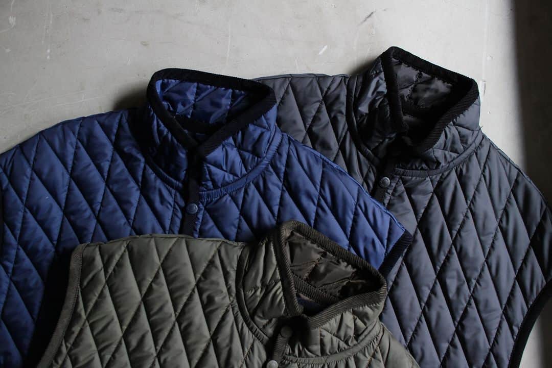 のインスタグラム：「▽ FW23 BB MICKFELD JM8391LV 100%POLYESTER ￥39,600 Color: 20 Olive Green 06 Harbour Blue 60 Lamp Black  50年を超える歴史がある 英国の老舗ファクトリーブランド 「Lavenham」とのコラボレーション  1900年代初頭の Baseballユニフォームの 補強パーツとして使われていた ストライプとスラントで形成した Jackmanオリジナルキルトパターンを採用した BB Mickfield  Baseballの投手が 登板終了とともに 着用するゆったりとした設計の アイシングポンチョをイメージした シルエットです  Waffle Midneckや GG Sweatとご一緒に」